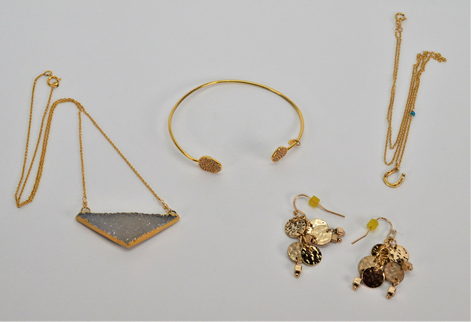 Gold Toned Costume Jewelry 4 Pieces: This four piece collection consists of gold toned jewelry. The bracelet by Tai fits up to a 7" wrist. The turquoise and horseshoe necklace is 18" long. The grey stone necklace is 16" long. The earring