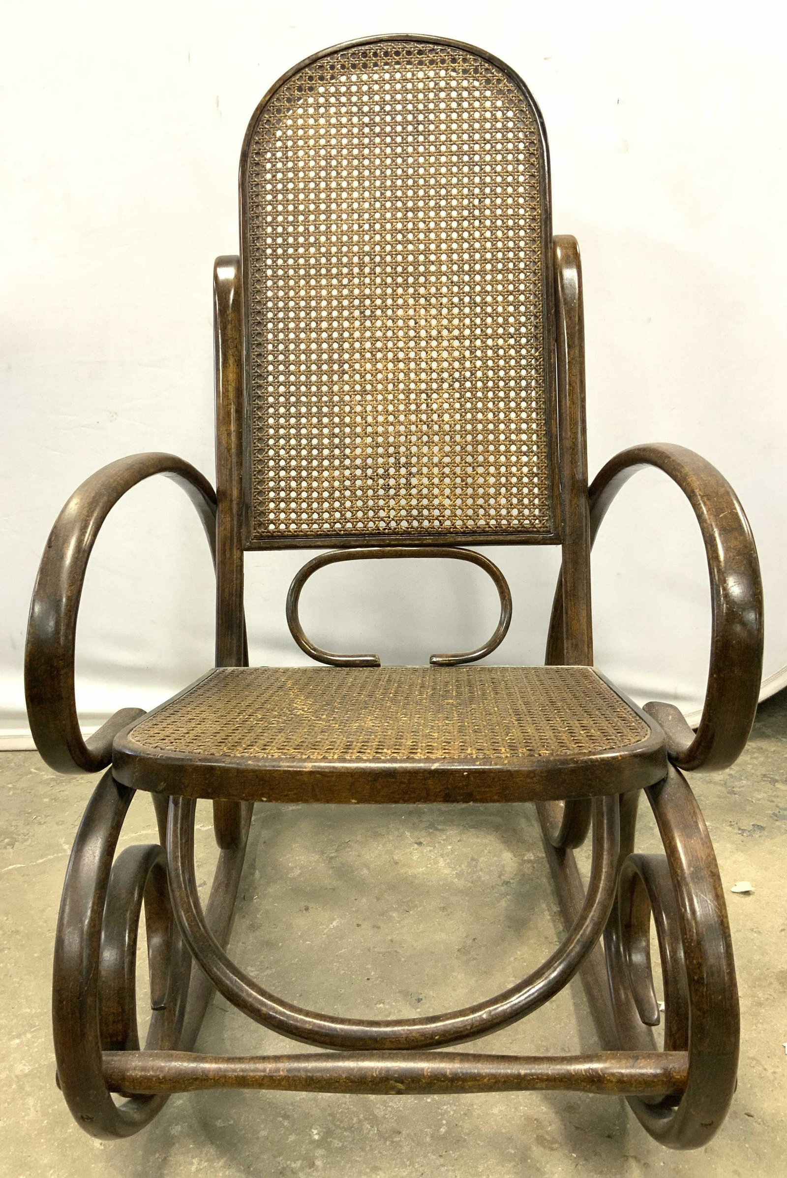 Antique Caned Bentwood Rocking Chair: Rocking chair is bentwood. Piece is vintage possibly antique. Chair is brown toned with caned seat & backrest. Piece measures approx 41 inches tall 22 inches wide 40 inches deep. Bentwood, bentwood ch
