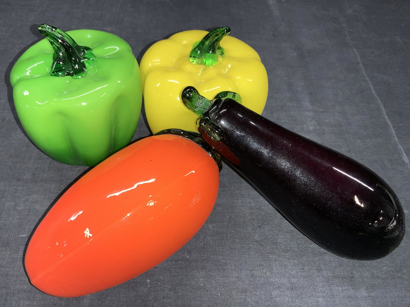 4 Art Glass Fruits & Vegetables: Hands blown art glass fruits and vegetables 2 peppers, green and yellow, 1 purple eggplant and 1 orange fruit, possibly a mango. Approximately 5 to 7 inches long. Minor wearing to surfaces. Hand blown