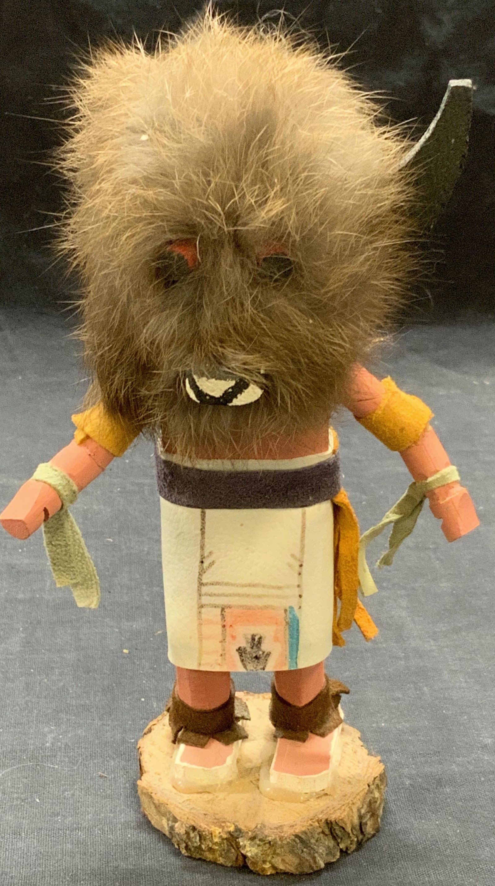 Signed Tribal Carved Wood Figurine: Appears to be a Native American Navajo Buffalo Kachina by Yazzie Signed tribal figurine. Composed of painted wood, leather, and fur. Signed to underside, illegible. Measures approx. 4.25 x 2.75 x 7.5 