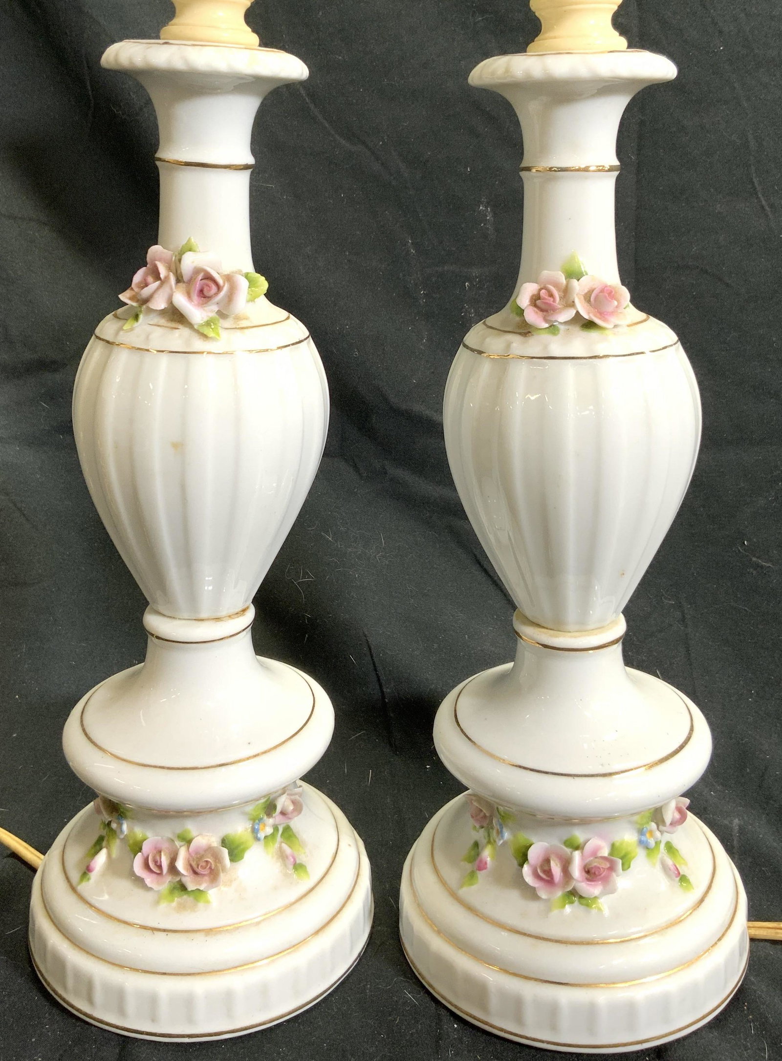 Vintage Pair Floral Detailed Porcelain Lamps: Lot includes 2 Lamps. Each are white with multi toned floral and leaf detail. Lamps have vase shaped. Each have thin Gilt areas. Lamps measure approx 13.25 inches tall 4 inches wide. Lamps, porcelain 