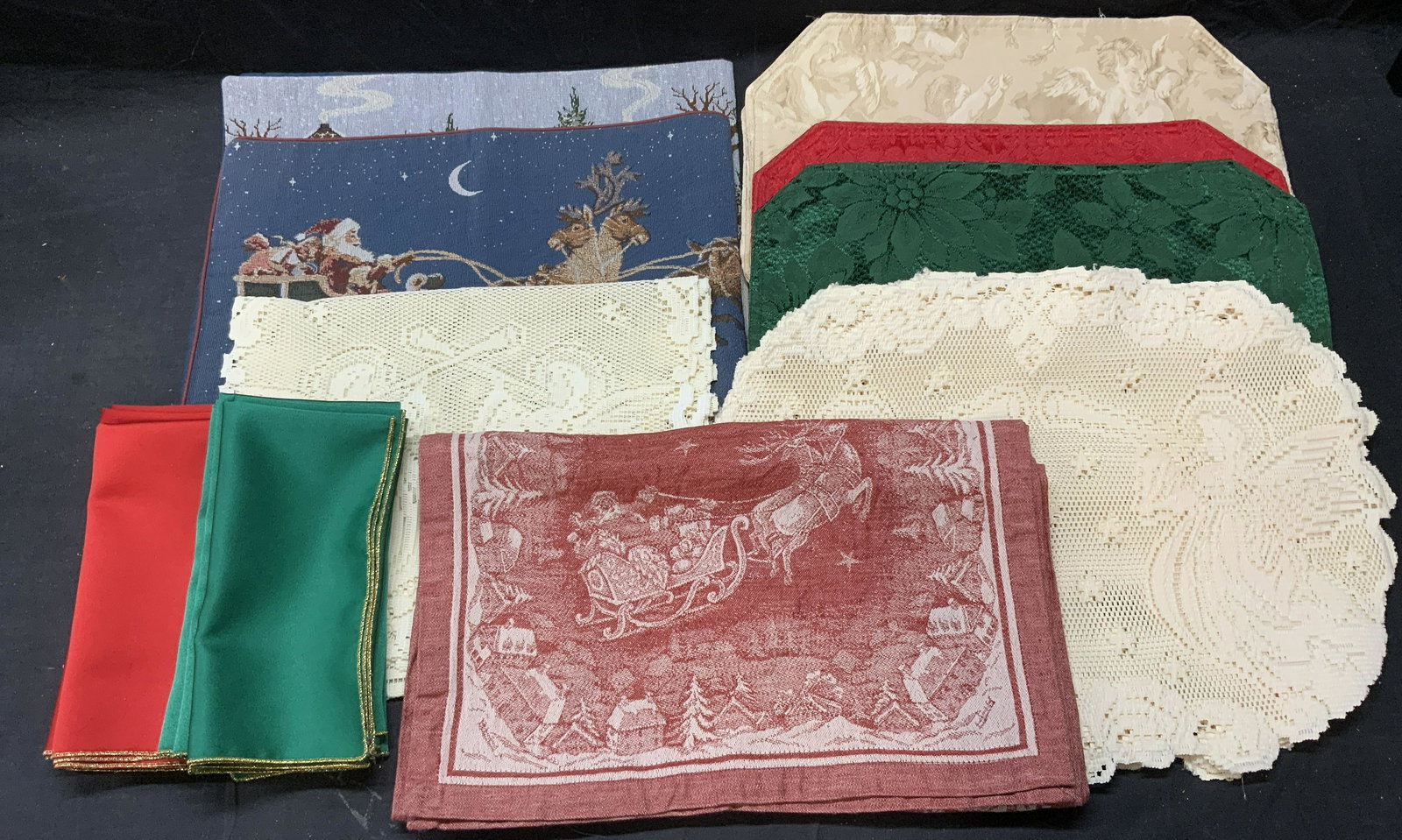 Lot 27 Holiday Napkins, Table Runner, Place Mats: Group lot of holiday dinner napkins, place mats, table runners, and tablecloths. Includes 4 red and 4 green dinner napkins, approx.18.5 x 19 inches each. 1 blue Santa and reindeer table runner, approx