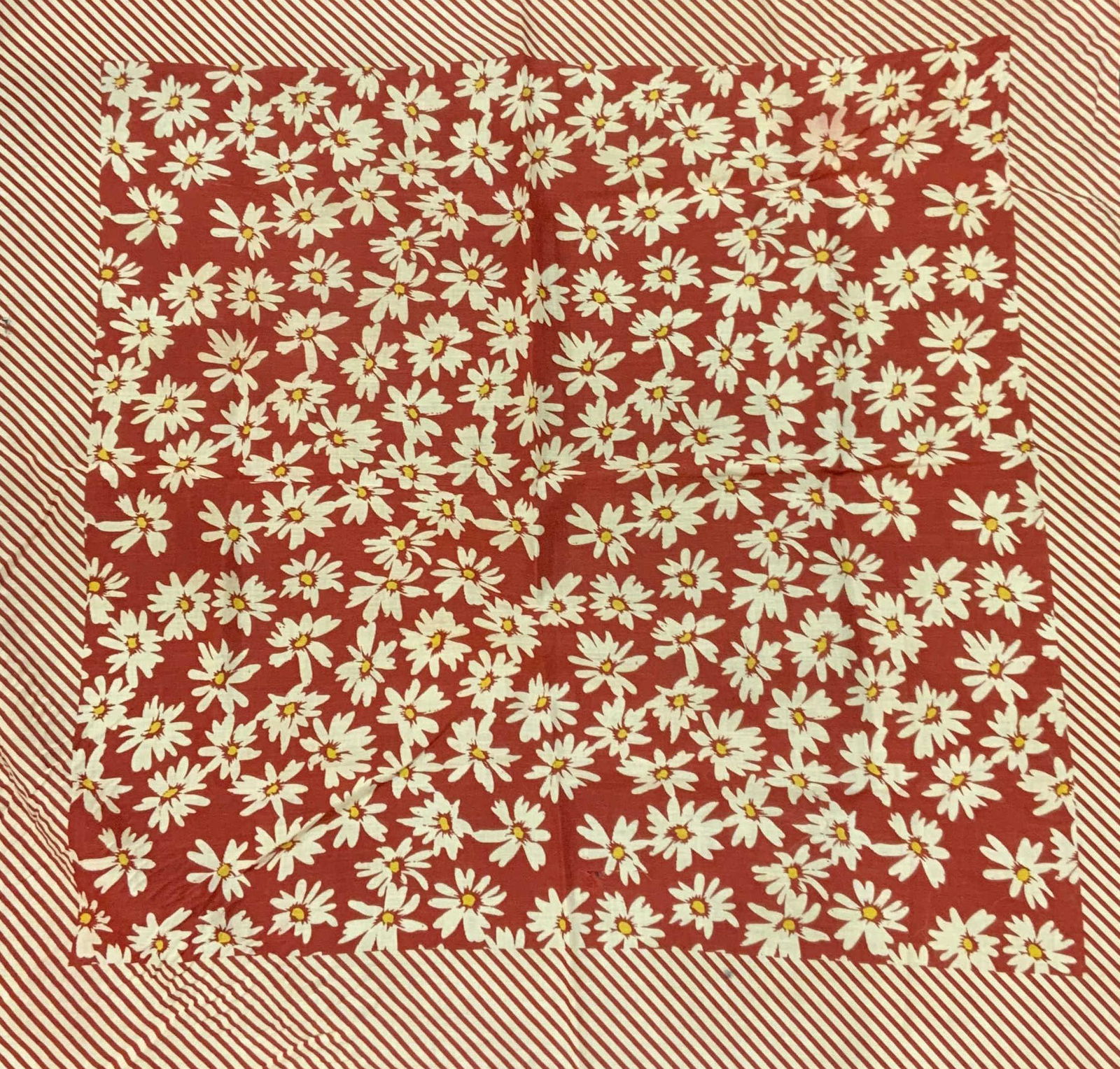 Red Floral Cotton Handkerchief: Red handkerchief with striped border and floral motif to center. Material feels like cotton. Wear to fabric consistent with exposure, some tearing observed. Measures approx. 20 x 20.25 inches. Handker