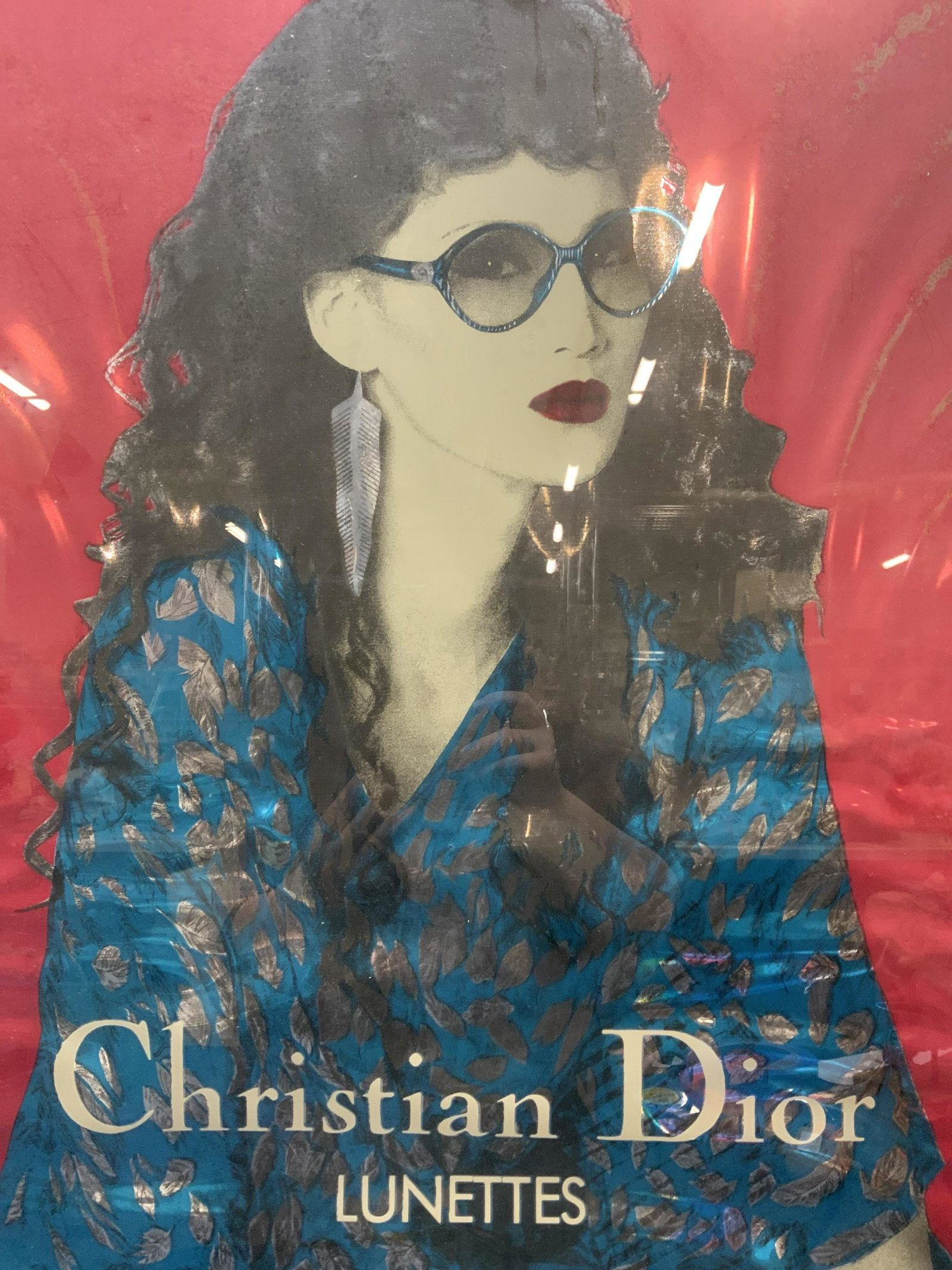 Christian Dior Lunettes Screen Print Advert: Framed Christian Dior Lunettes advertisement screen print. Subject depicts a woman wearing sunglasses. Framed in silver tone metal frame. Not examined out of frame, buckling to paper observed. Measure
