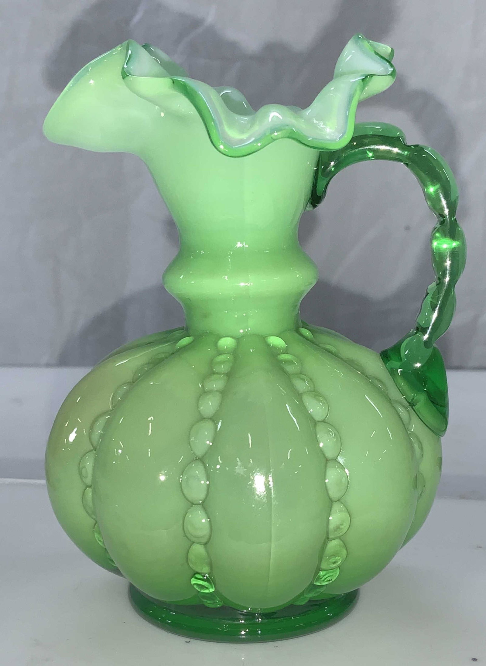 MC Handkerchief Glass Ewer: Art glass miniature ewer with handle in opaque green glass. Measures 4.5 in ht, app 3.5 in. Wide. Art glass, mid century Glass ewer, decorative arts, decorative glass ware , Tabletop Display , green G