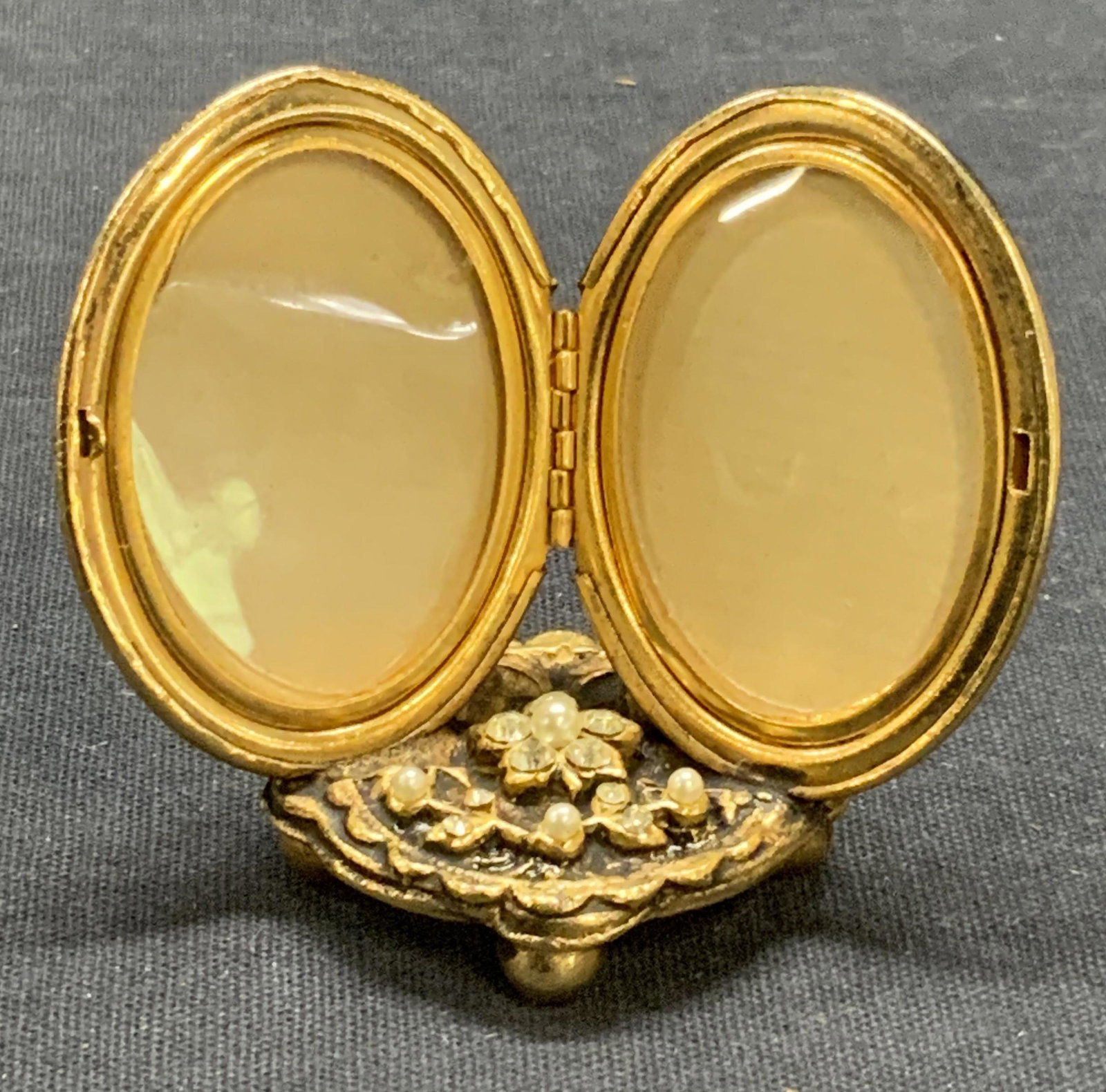Gold Tone Crystal & Faux Pearl Display Locket: Gold tone chased metal display locket with faux pearl and crystal decoration. Measures approx. 2.25 x 1 x 1.75 inches. Some surface wear consistent with exposure. Locket, display locket, gold tone loc