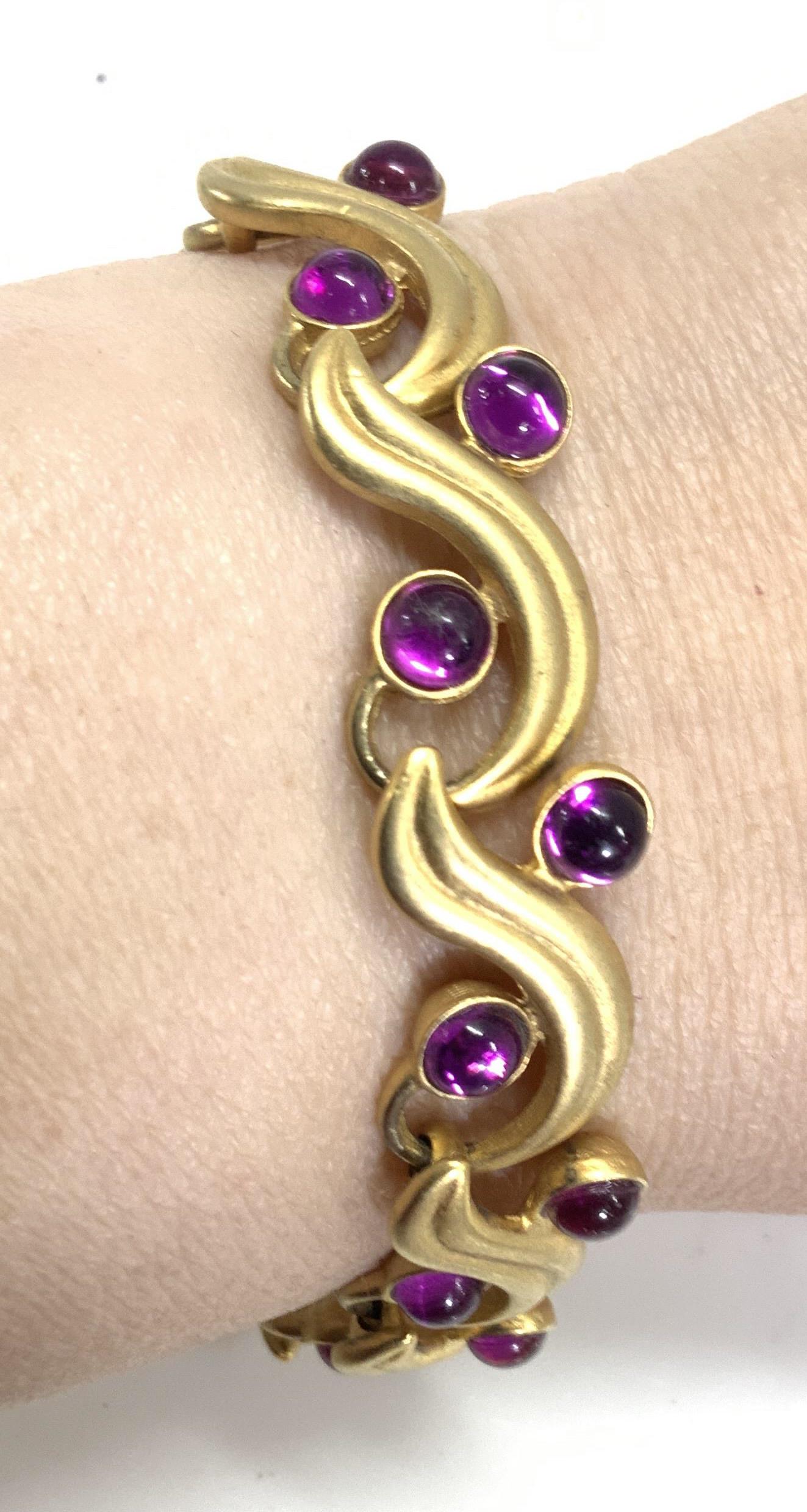 DAVID Sgn Gold Tone & Amethyst Glass Bracelet: Brushed gold tone bracelet with amethyst colored glass cabochons, secure box clasp. Signed David. 7.75 in. L Signed jewelry, costume jewelry cocktail jewelry, goldtone bracelet, Designer David Gold to