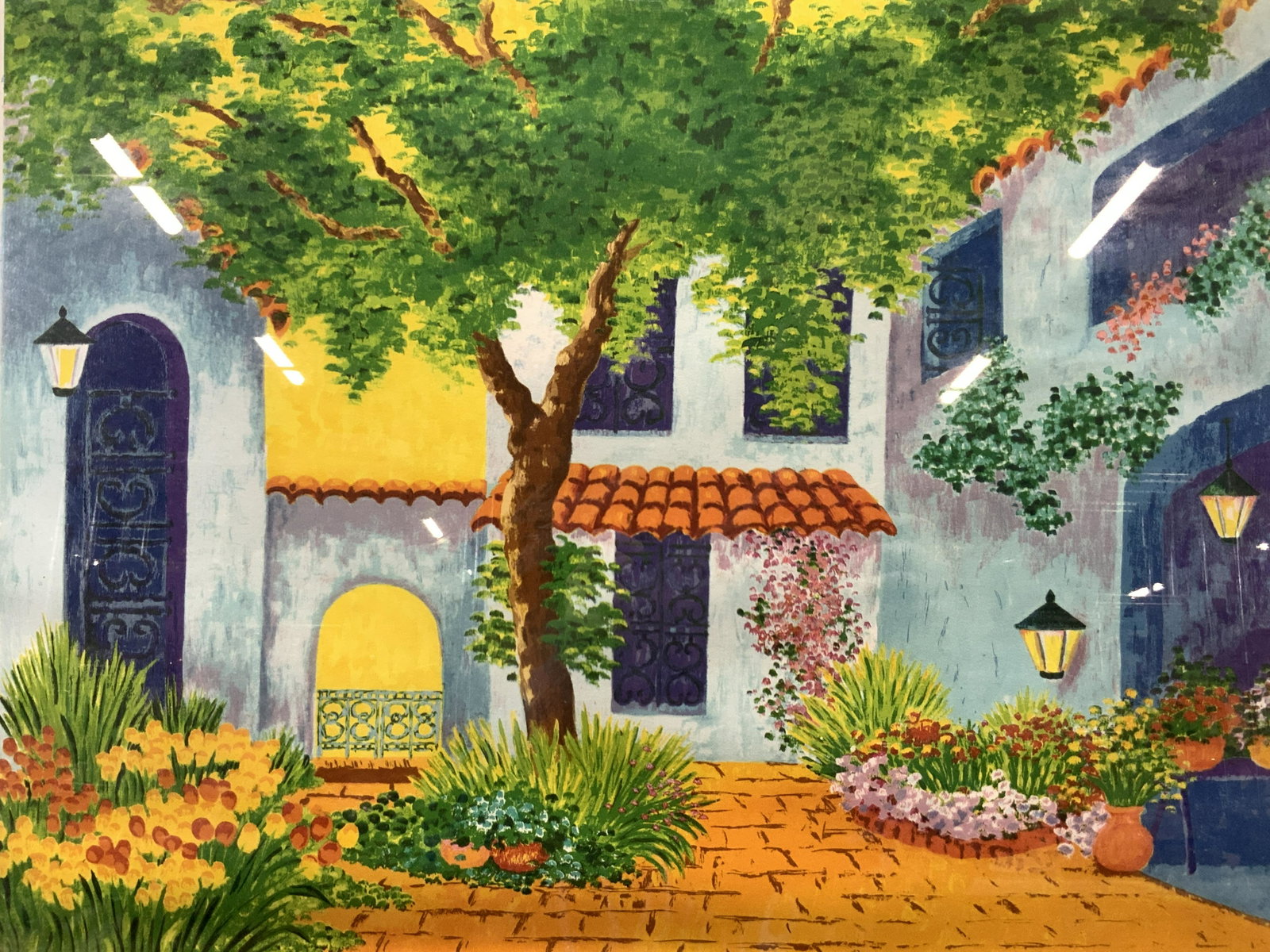 Framed villa Court Yard Silk Screen: Framed silk screen depicting the exterior court yard of a villa with curved roof tiles and growing flowers and trees within the court yard. Framed in gray toned wooden frame with double mat boards, of