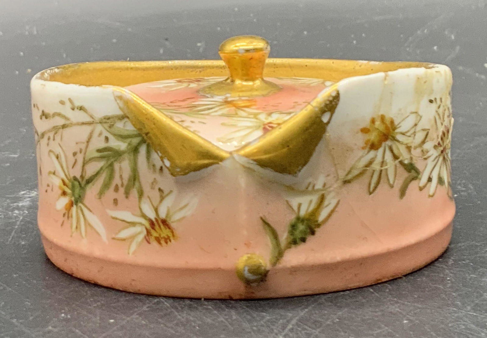 SM LIMOGES FRANCE Hand Painted Porcelain Pill Box: A vintage hand painted porcelain pill box. Lidded. Pink, white, green, and gold tone hues. Florals to obverse and interior. Circular form. Dress shirt motif to the rim. Underside marked LIMOGES FRANCE