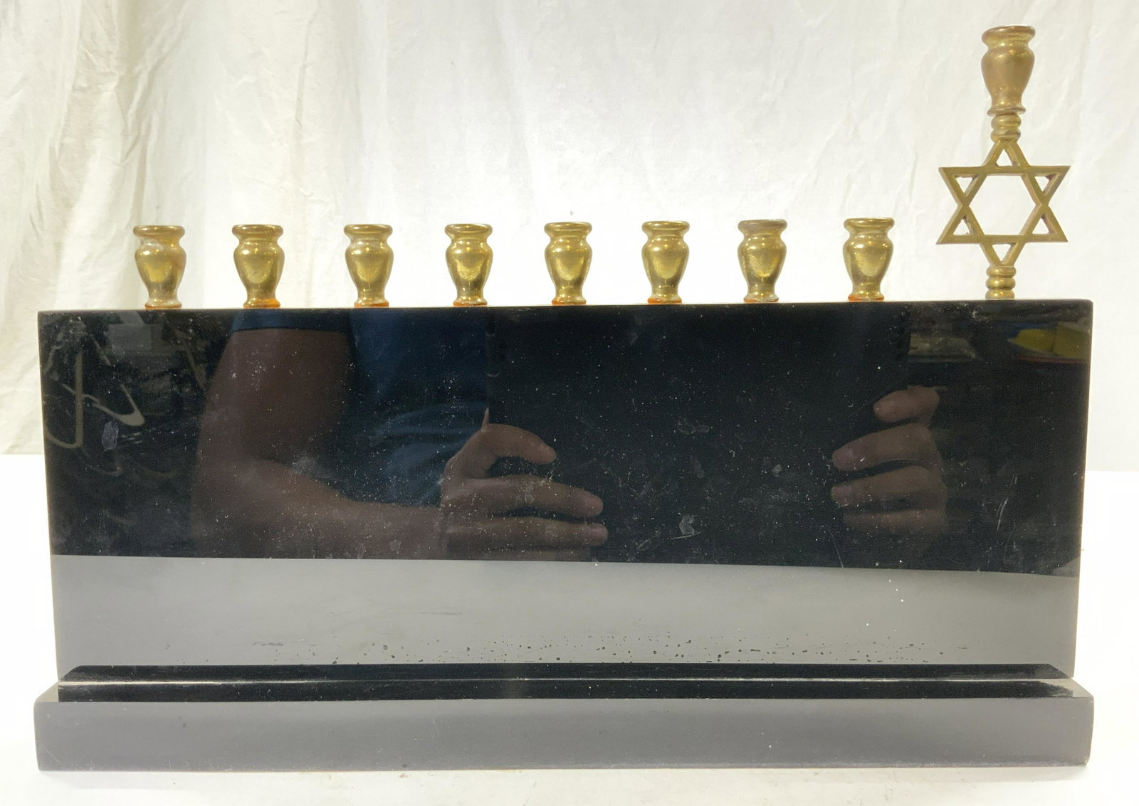 Black Lacquer & Brass Judaica Menorah: Menorah is black with gold toned brass candle areas. Piece has 9 candle areas, 1 with Star Of David Detail. Piece appears to possibly be lacquered possibly acrylic. Piece measures approx 13 inches lon