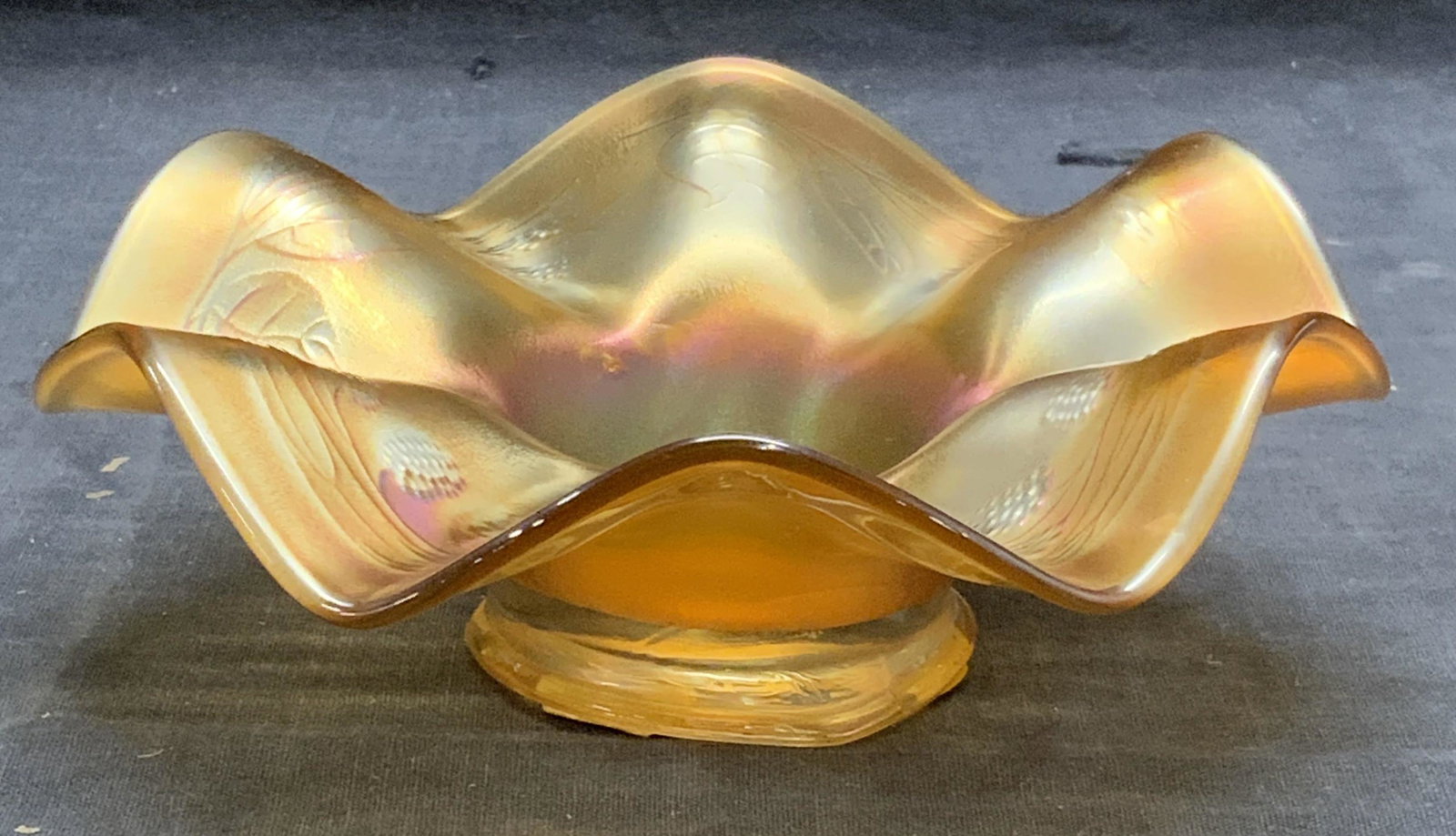 Orange Carnival Art Glass Handkerchief Vessel: Orange iridescent carnival art glass vessel handkerchief and botanical pattern. Some surface wear consistent with exposure. Measures approx. 6.5 inches wide and 2.25 inches tall. Art glass, carnival g