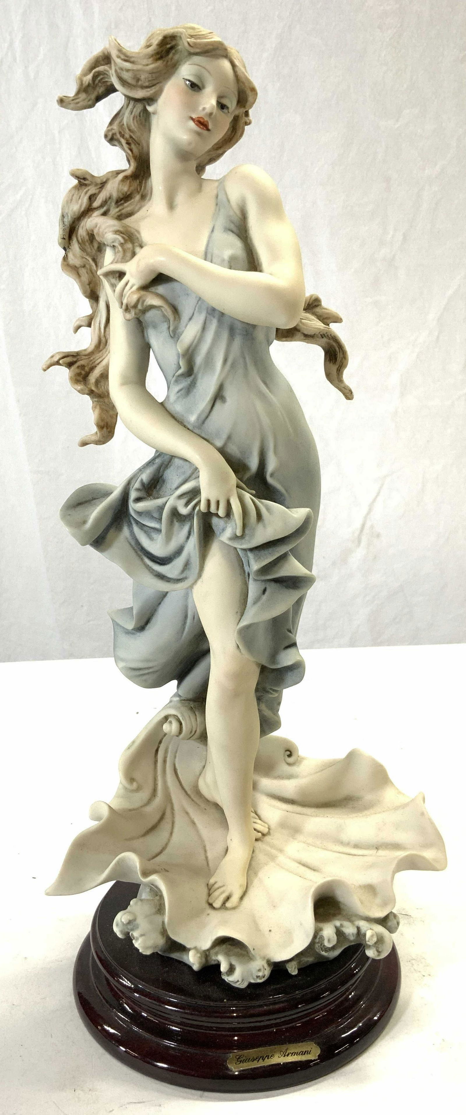 GIUSEPPE ARMANI BIRTH OF VENUS Porcelain Sculpture: Sculpture is signed GIUSEPPE ARMANI. Piece appears to be porcelain possibly composite. Piece depicts long haired female figure wearing light blue dress standing in clam shell. Underside has tag which