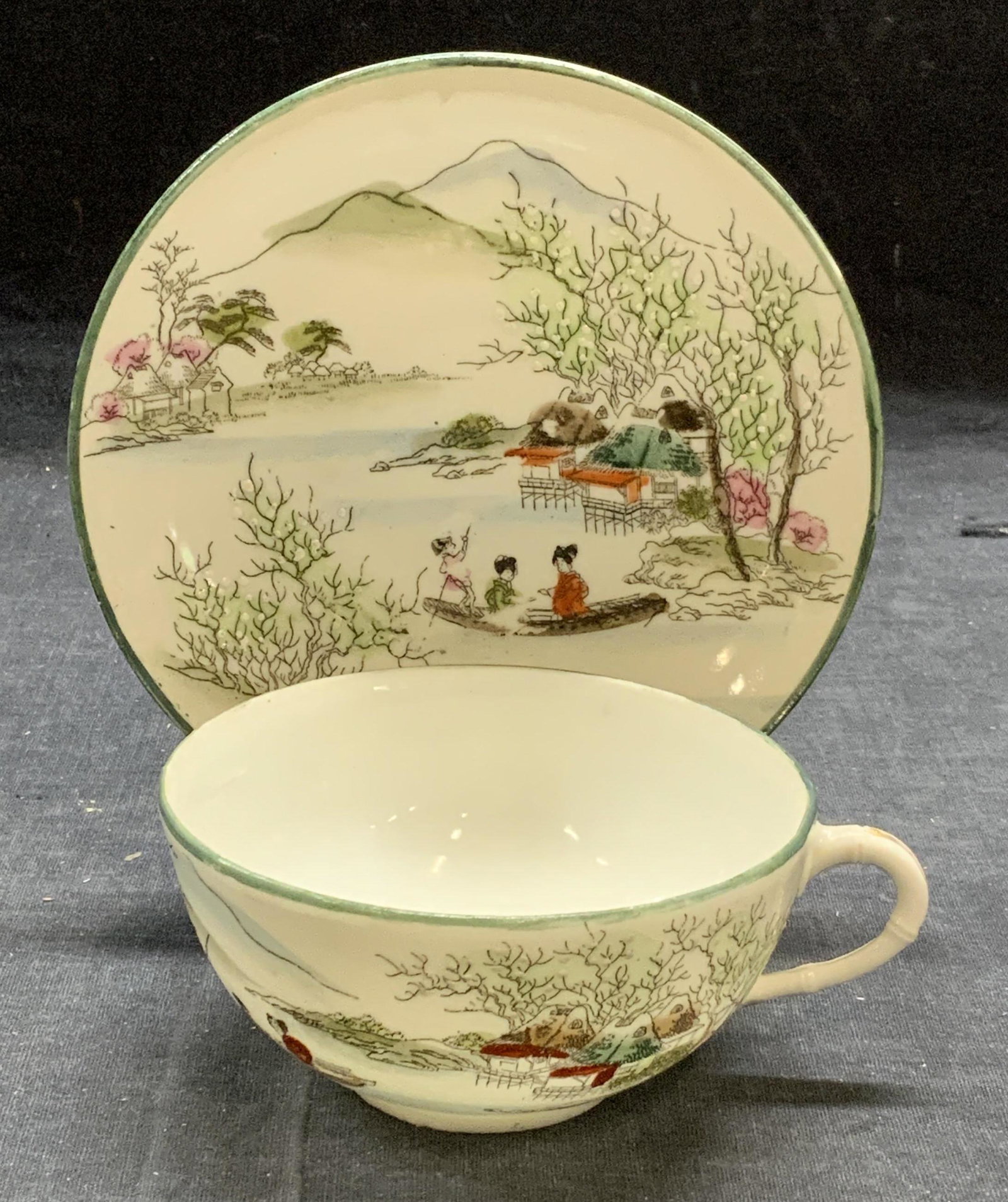 Vintage Nippon Porcelain Teacup & Saucer Japan: Vintage Nippon porcelain teacup and saucer with Asian figural and landscape motif. Marked Nippon to underside of saucer. Some surface wear consistent with exposure. Saucer measures approx. 5.25 inches