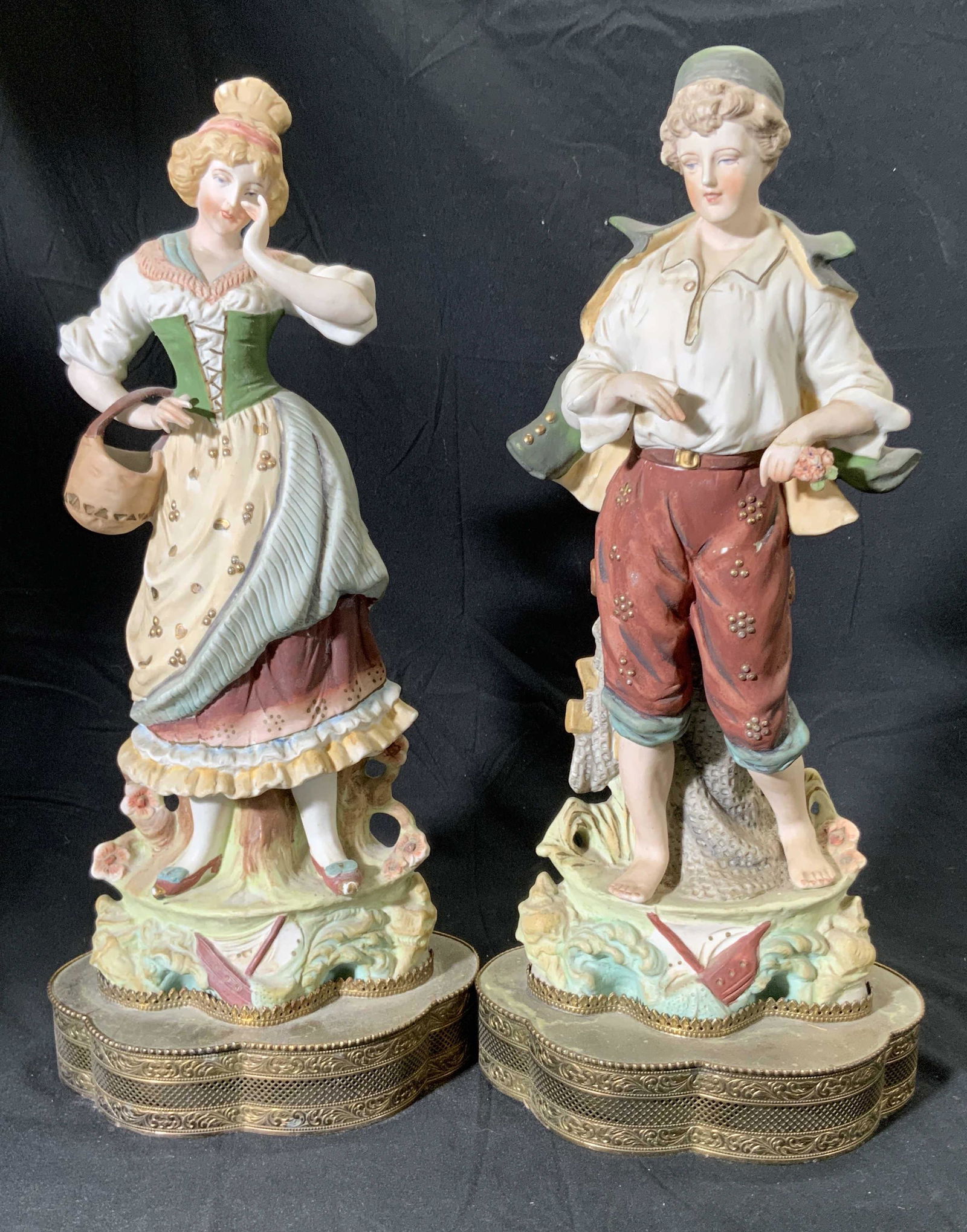 Pair XL Vintage Hand Painted Porcelain Figurals: A pair of vintage hand painted porcelain figurals. One man, one woman. Pieces are attached to brass hued metal base. Measures approx 16.5H x 5.5W in. Similar in size. Some chipping, losses, and surfac