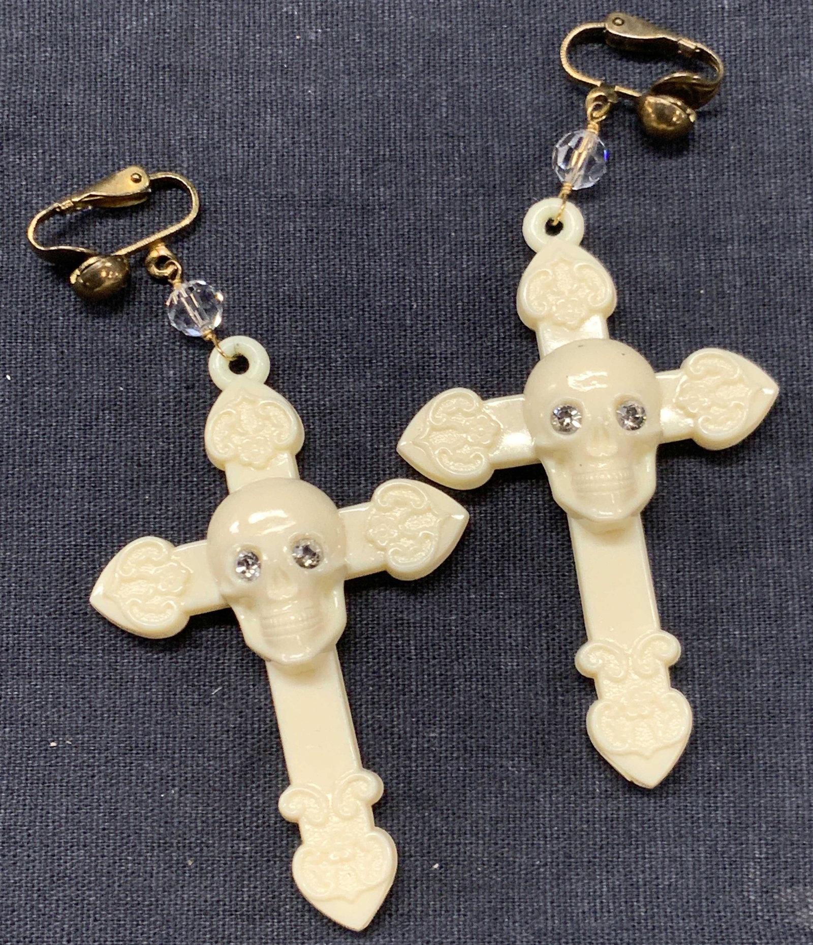 Artisan Skull Cross Costume Earrings, Clip Ons: Set of artisan made clip on resin earrings with crosses with skulls in the centers and brass made clips. Approximately 3.25 inches long. Minor wearing to metal clips. Artisan earrings, clip on earring
