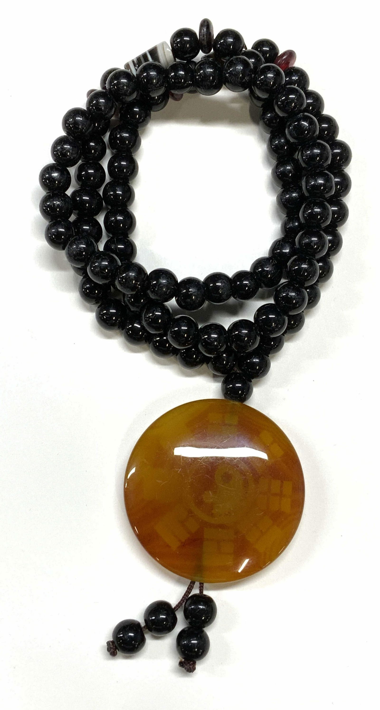 Gemstone Beaded Yin Yang Pendant Necklace: Possibly black onyx beaded necklace with possibly citrine pendant with yin Yang motif. Necklace measures approx. 26 inches long. Pendant measures approx. 1.75 inches diameter. Some surface wear consis