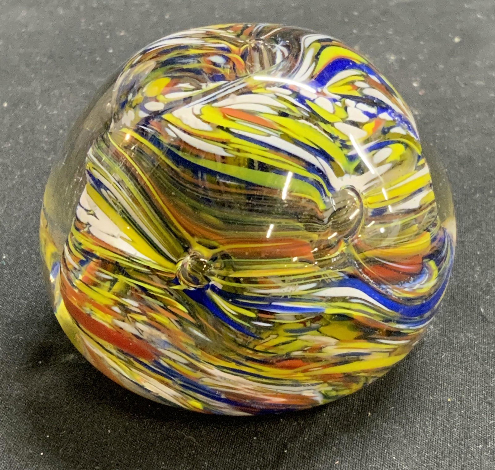 MURANO Style Art Glass Swirl Paperweight: Murano style swirled art glass paperweight in hues of yellow, blue, red, and white. Measures approx. 2.25 inches diameter. In good condition, minor surface wear consistent with exposure. MURANO style 