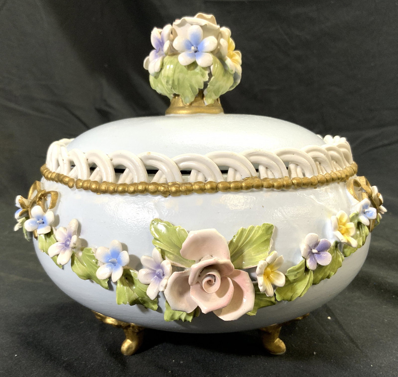 CAPODIMONTE Italian Porcelain Footed Lidded Vessel: Underside reads CAPODIMONTE MADE IN ITALY. Vessel is porcelain and includes lid. Piece has 3 gold toned feet. Vessel has intricate multi toned floral, leaf & ribbon detail. Lid has floral handle. Meas