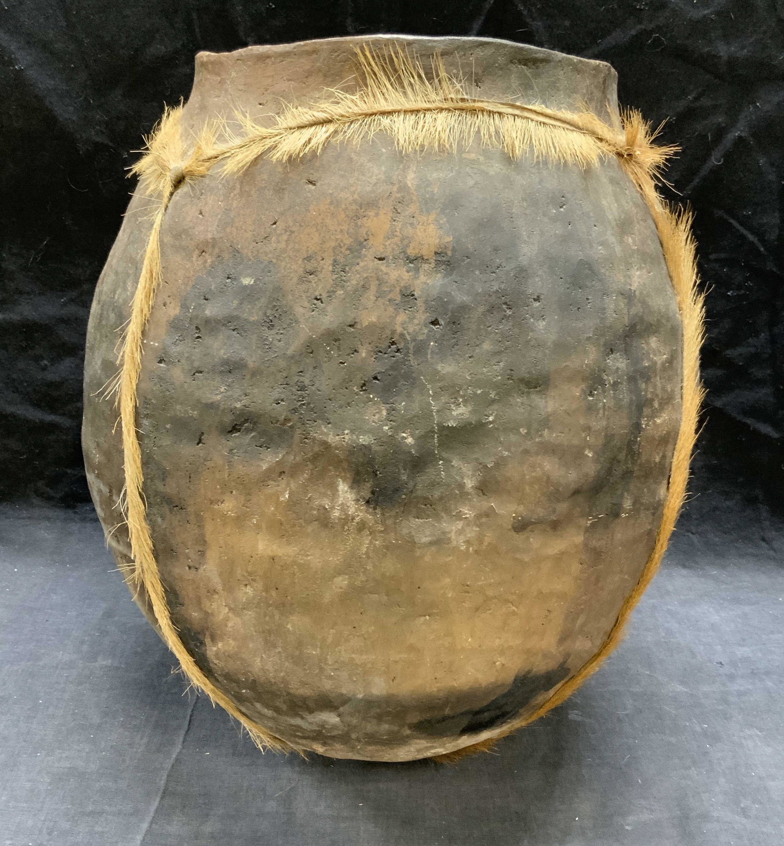 Vintage Tribal Pottery & Fur Vessel: Vintage, possibly antique, tribal pottery vessel with fur decoration. Surface wear consistent with exposure, chip to rim observed. Measures approx. 10 inches diameter and 13 inches tall. Tribal potter