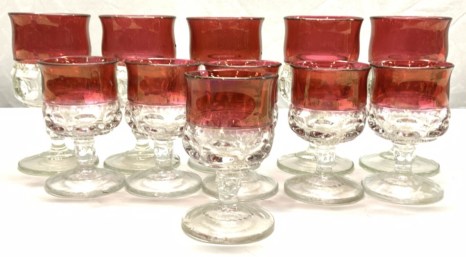 Set 11 Mid Century Cranberry & Clear Wine Glasses: Mid century bohemian style heavy glass stemware. Upper cranberry border with embossed circle and dot pattern. 2 sizes with same shape. Larger glass measures 5.75 x 3.5 in. Smaller glass measures 4.5 x
