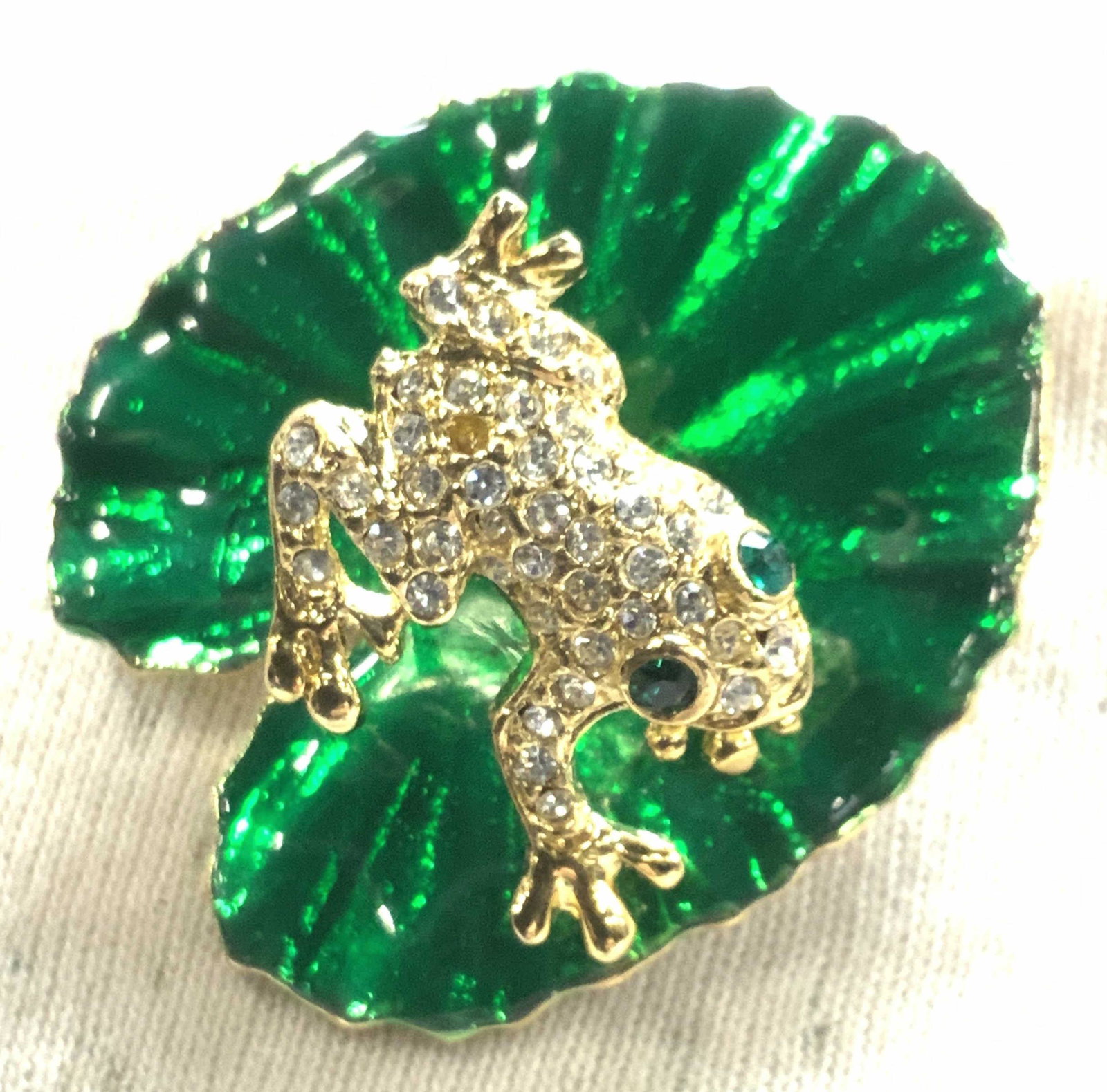 Enamel Water Lily Pad Brooch w Crystal Frog: Glossy green enamel water Lily on gold tone metal with pave crystal frog suspended over lily pad with a spring. Frog has green crystal eyes. Measures 1.25 x 1.25 in. Frog brooch, enamel and crystal pi