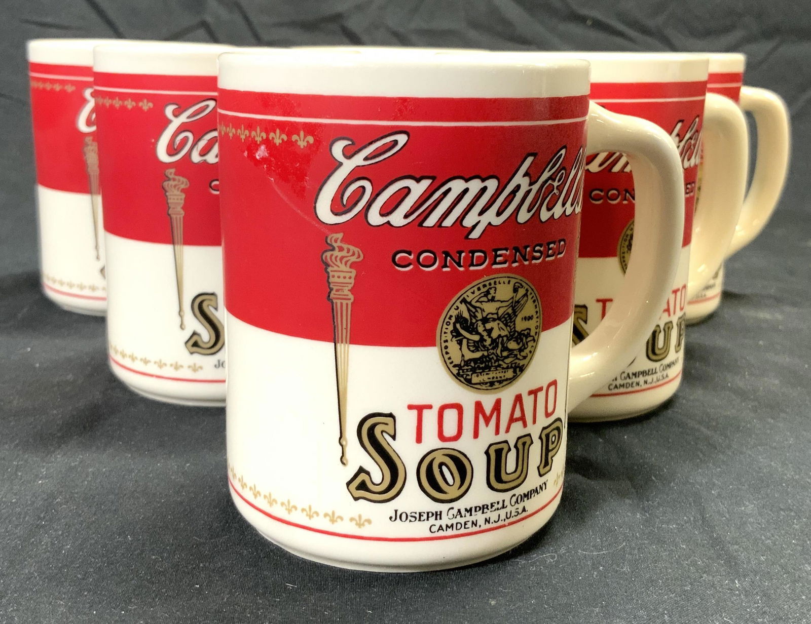 CAMPBELLS TOMATO SOUP Set 6 Porc Coffee Cups: Each cup resembles CAMPBELLS TOMATO SOUP can and label. Undersides read USA. Lot includes 6 cups, each are porcelain. Each measures approx 3.75 inches tall 3 inches wide 4.25 inches deep. CAMPBELLS to
