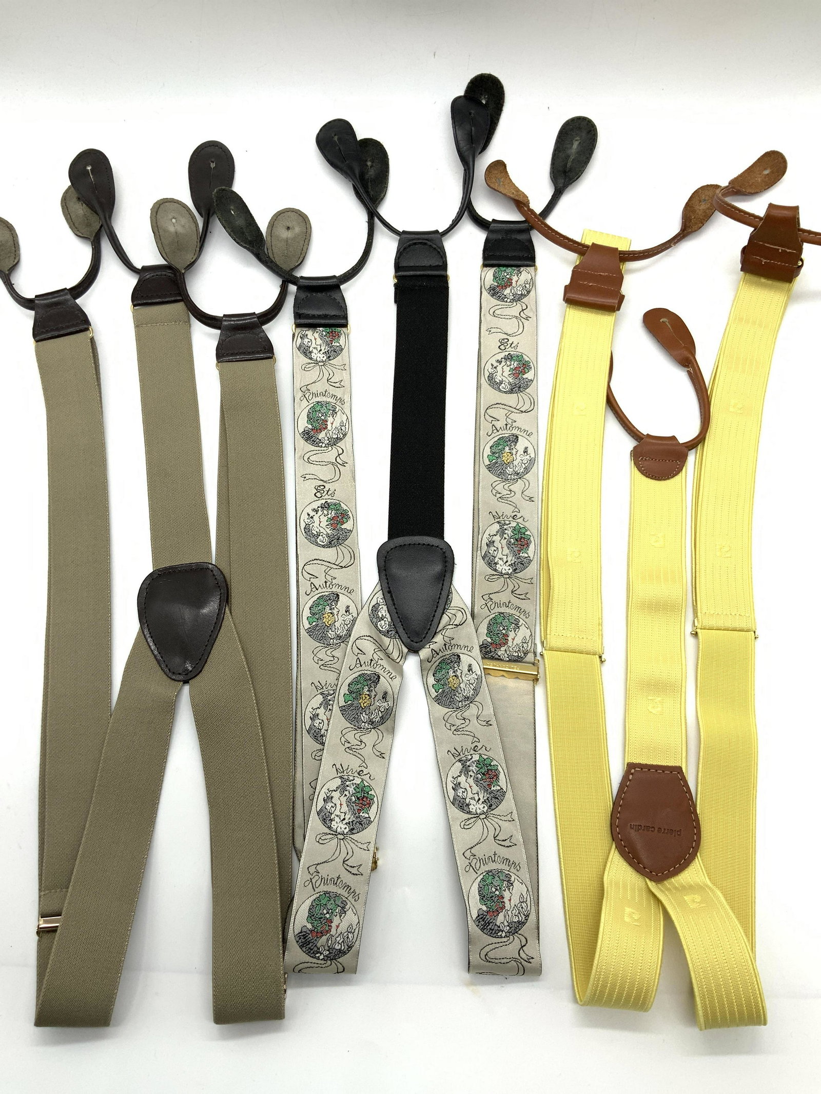 3 Assorted Suspenders, Pierre Cardin & More: Group lot of 3 Assorted suspenders. 1 marked Pierre Cardin with yellow bands, 1 with off gray bands and 1 with various profiles of women. All with colored leather ends. Approximately 30 inches long. M