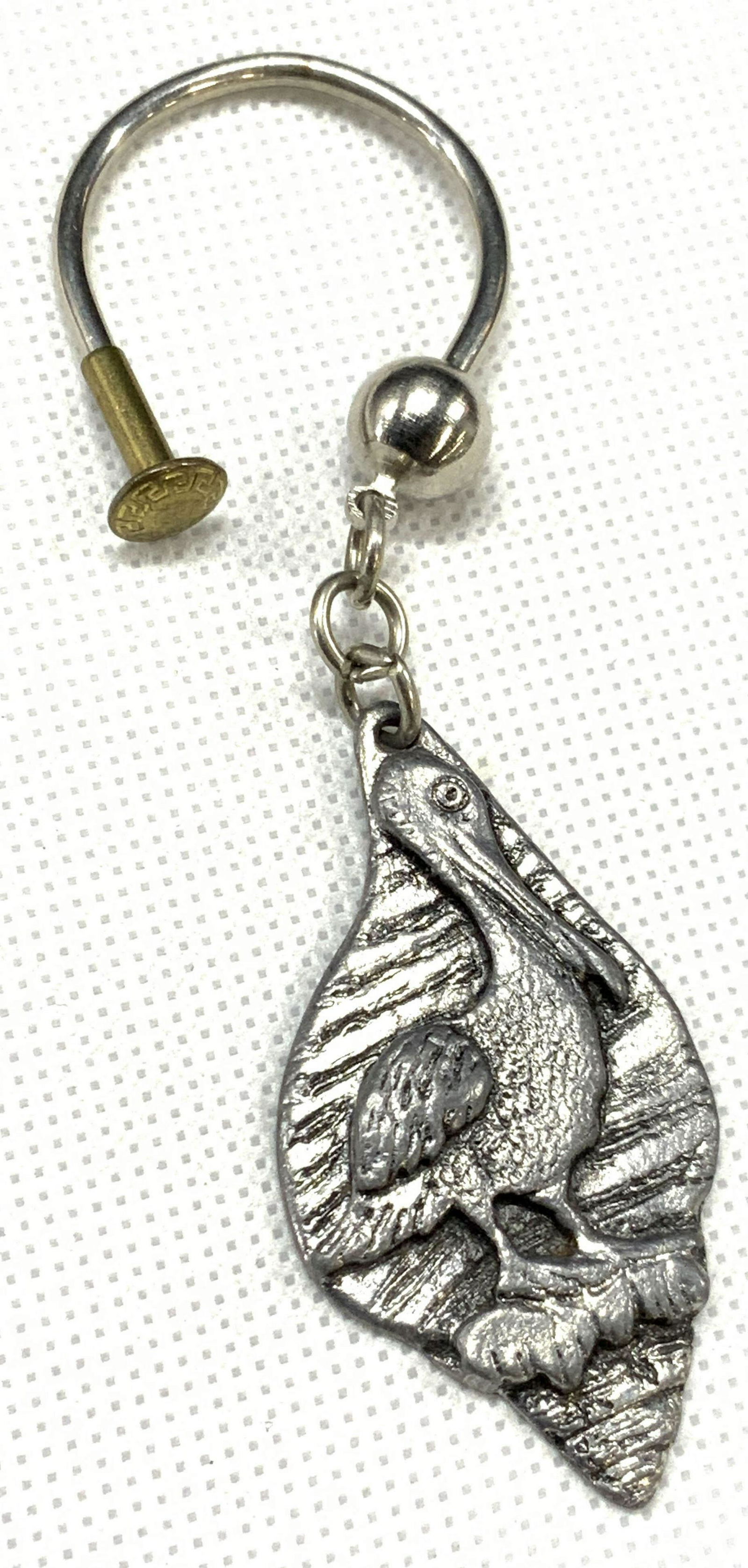Metzke Stamped 1976 Pewter Pelican Keychain: Marked in backside Metzke 1976 Depicts a raised image of Pelican within pewter with white metal loop. Approximately 4 inches long. Minor wearing due to age and use. Pewter keychain, Metzke keychain, P