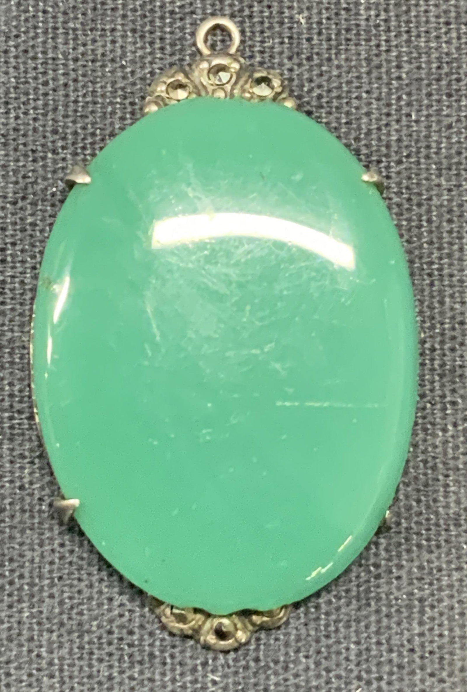 Sterling Silver & Marcasite Green Cabochon Pendant: Sterling and marcasite pendant with smooth green Cabochon. Marked sterling to underside. Measures approx. 1.5 x 7/8 inches. Surface wear consistent with exposure. Total weight 7.2 grams. Estate jewelr