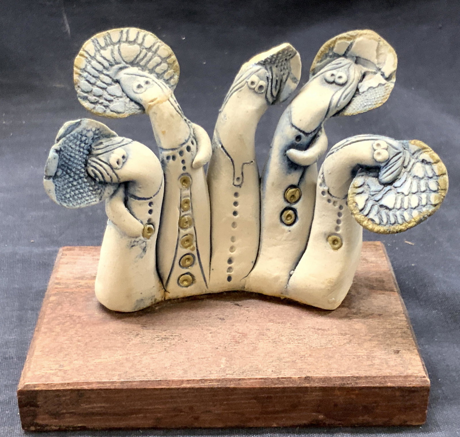 Ruth Barkai Hand Crafted Pottery Sculpture: Marked on underside Hand made Ruth Barkai, Lohmei Hagetaot Depicts 5 pottery figures in curved positions with tall head pieces. Affixed to wooden base, approximately 5 inches tall and base approximate