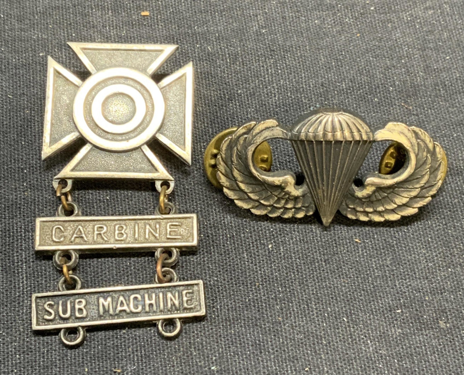 Lot 2 Vintage Sterling Silver Military Pins: Lot of 2 vintage sterling silver military pins. 1 pin United States Military sharpshooter qualification, pendants read Carbine and Sub Machine. Marked sterling to underside. Measures approx. 2 x 1 inc