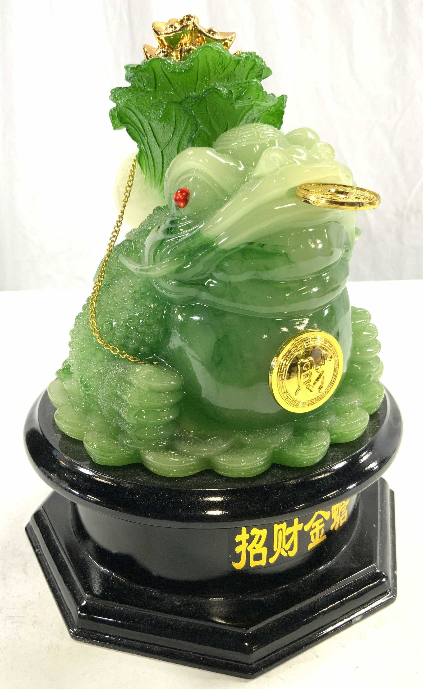 Feng Shui Jadeite Style Money Frog Statue: Statue is jadeite style heavy plastic material. Piece depicts frog with flower on head & coin in mouth with medallion on chest. Base is black toned appears to be wooden. Base has gold toned Asian char