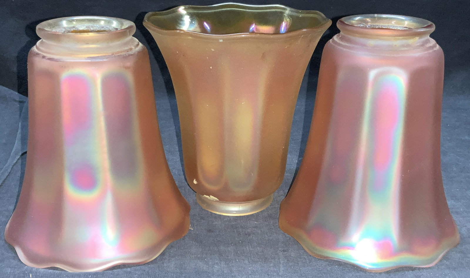 Set 3 Orange Carnival Glass Lamp Shades: Set of 3 orange toned iridescent carnival glass lamp shades with rounded rim. Approximately 5.5 inches tall and 5 inch diameter. Moderate wearing to glass ends, evident cracking to narrow ends of shad