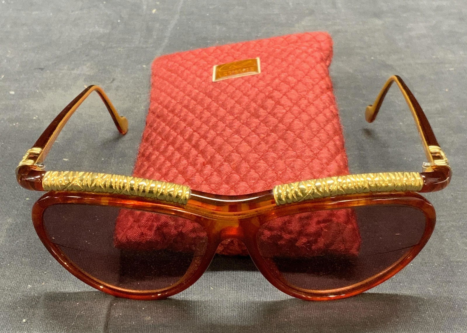 Christian LACROIX Orange/Gold Sunglasses: French designer, made in Germany. Christian LACROIX orange and gold toned acrylic frame sunglasses. Includes case. Designer label to arm. Some surface wear consistent with exposure. Measure approx. 5