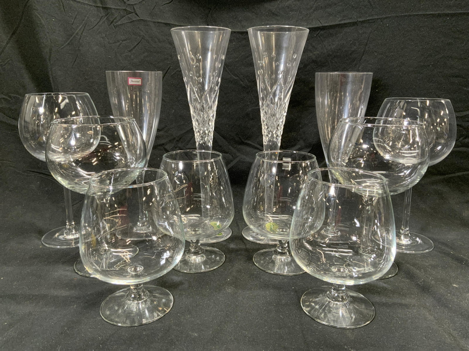 Lot 12 Crystal & Glass Stemware: Lot includes 2 WATERFORD CRYSTAL champagne flutes, 2 BACCARAT Crystal flutes, 4 brandy glasses 2 wine glasses 2 wide basin wine glasses. Waterford flutes measure approx 11 inches tall 3.25 inches wide