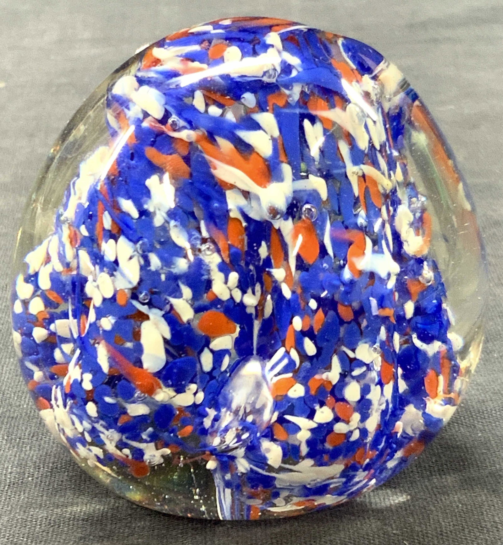 Art Glass Paperweight, India: Marked India on underisde. Art glass paperweight with red white and blue interior design within the clear exterior glass. Approximately 3 inches tall. Minor wearing to underside. Art glass, art glass 
