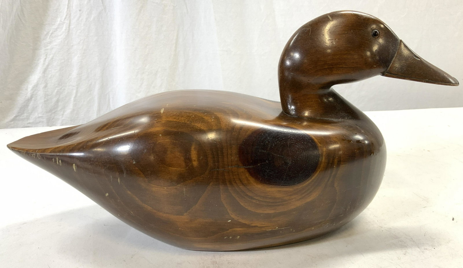 Vintage Carved Wooden Duck Decoy: Underside is trademarked. Piece is brown toned & wooden. Decoy is possibly hand carved. Piece measures approx 8 inches tall 6.5 inches wide 16 inches deep. Duck decoy, vintage duck decoy, wooden duck 