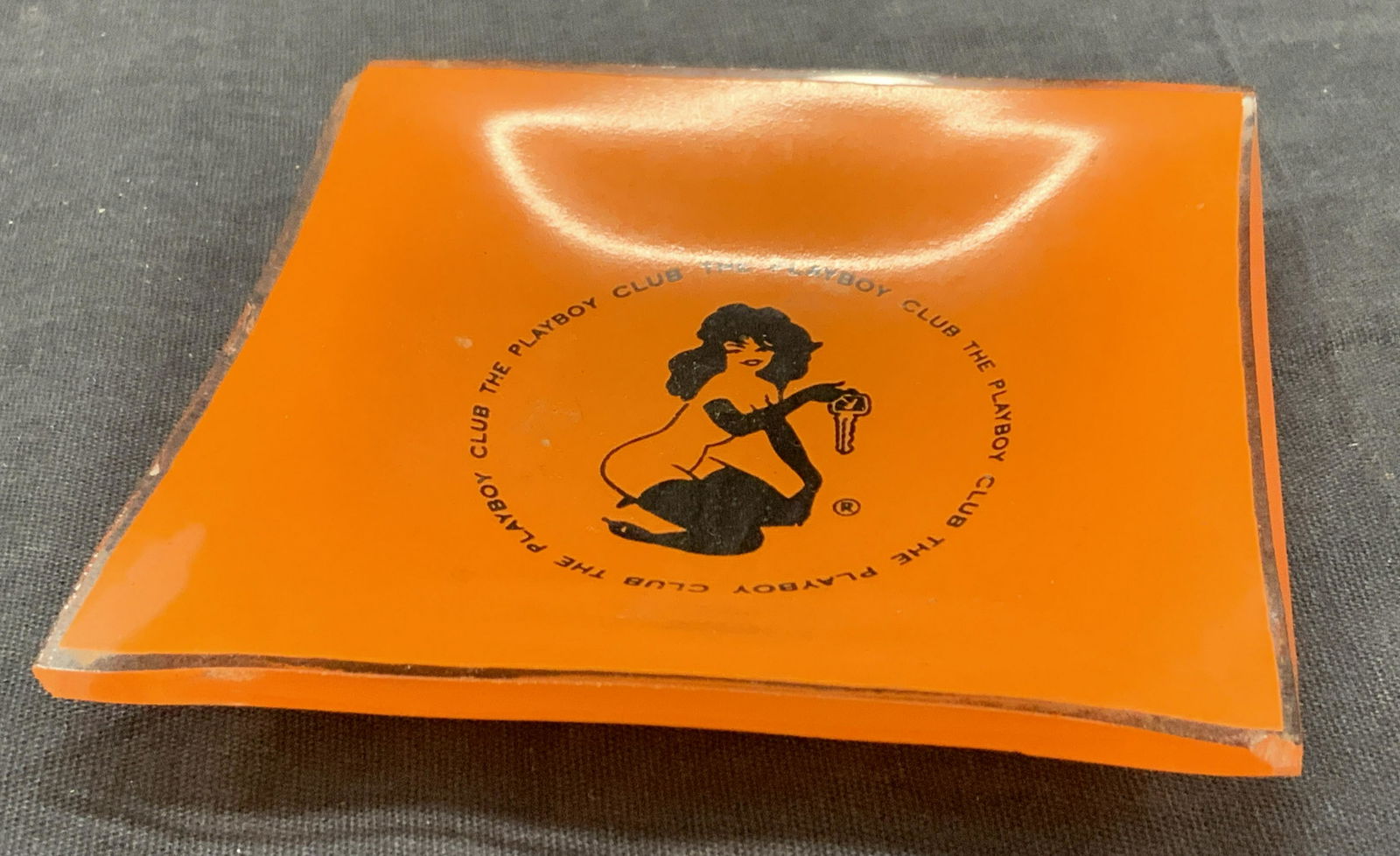 Vintage Orange Glass Playboy Figural Trinket Dish: Vintage glass trinket dish, orange in town with black pin up girl in center with The Playboy Club around the figure. Approximately 3.75 x 3.75 inches Evident chip to corner of dish. The Playboy club g