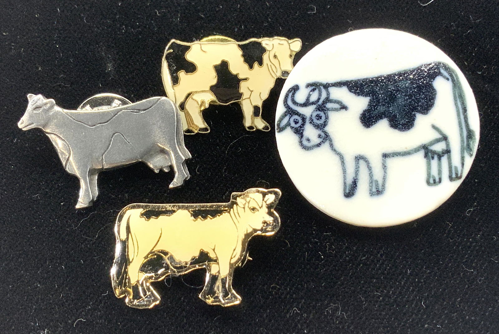 Pewter, Enamel , & Ceramic Cow Lapel Pins, 4: Cow lapel pins and brooch, 2 are black and white enamel lapel pins outlined in goldtone, app 1 in. Round ceramic cow brooch, 1 1/8 in. Pewter cow lapel pin that is signed on back, reads Made in Vermon