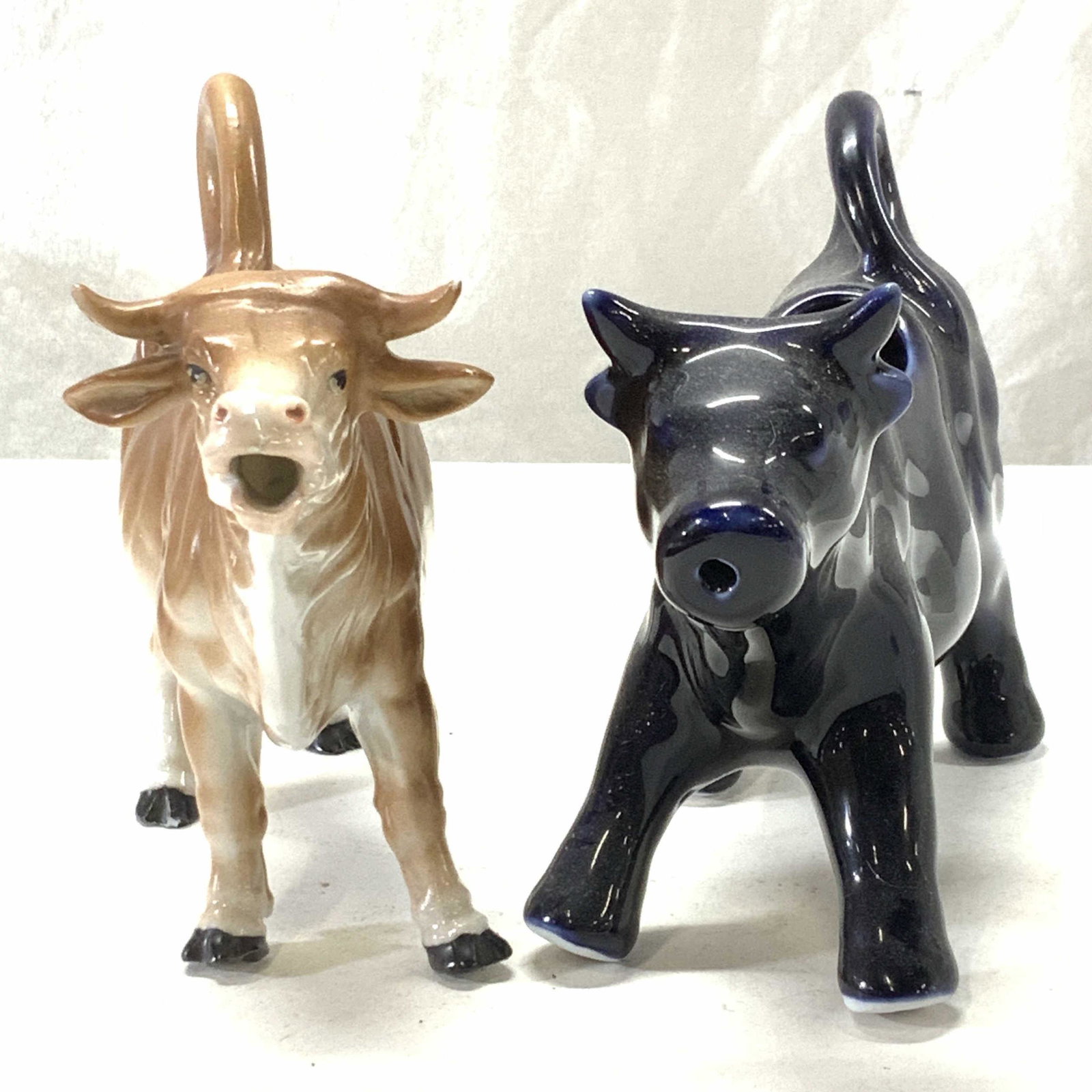 Pair Porcelain Cow Figural Creamers: Cobalt Cow Creamer, 7.5 x 5 x 2.5 in. Brown and white matte porcelain cow creamer , 7.25 in. L x 5 in. Ht x 2.25 in. W Property of Manhattan New York City Americana, Macys, & Milk Bottle collectors es