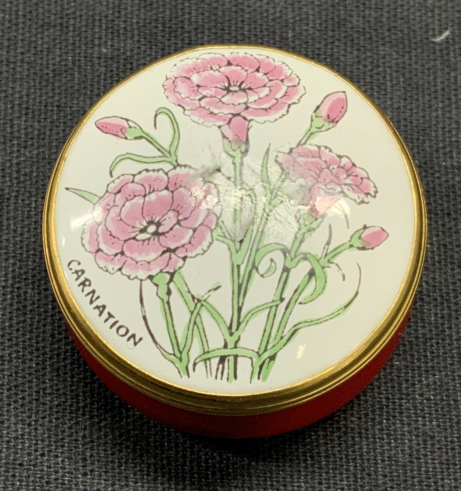 CRUMMLES Carnation Enameled Metal Pill Box England: CRUMMLES enameled Metal pill box with carnation motif. Trademarked to underside. Measures approx. 1.25 inches diameter and .5 inches tall. Made in England. Some surface wear consistent with exposure. 