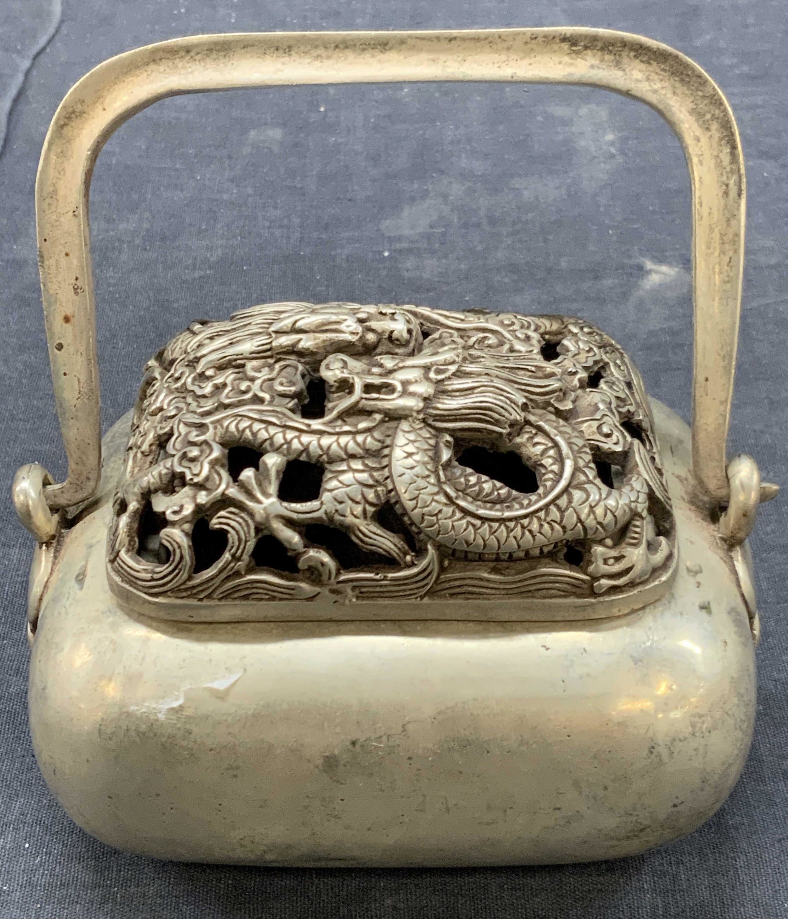 Stamped Silver Toned Asian Incenser: Stamped on underside with Asian characters. A Incenser with box and top handle with top lid having cut outs and dragon motifs. Approximately 4 inches tall, top handle is approximately 5.25 inches fall
