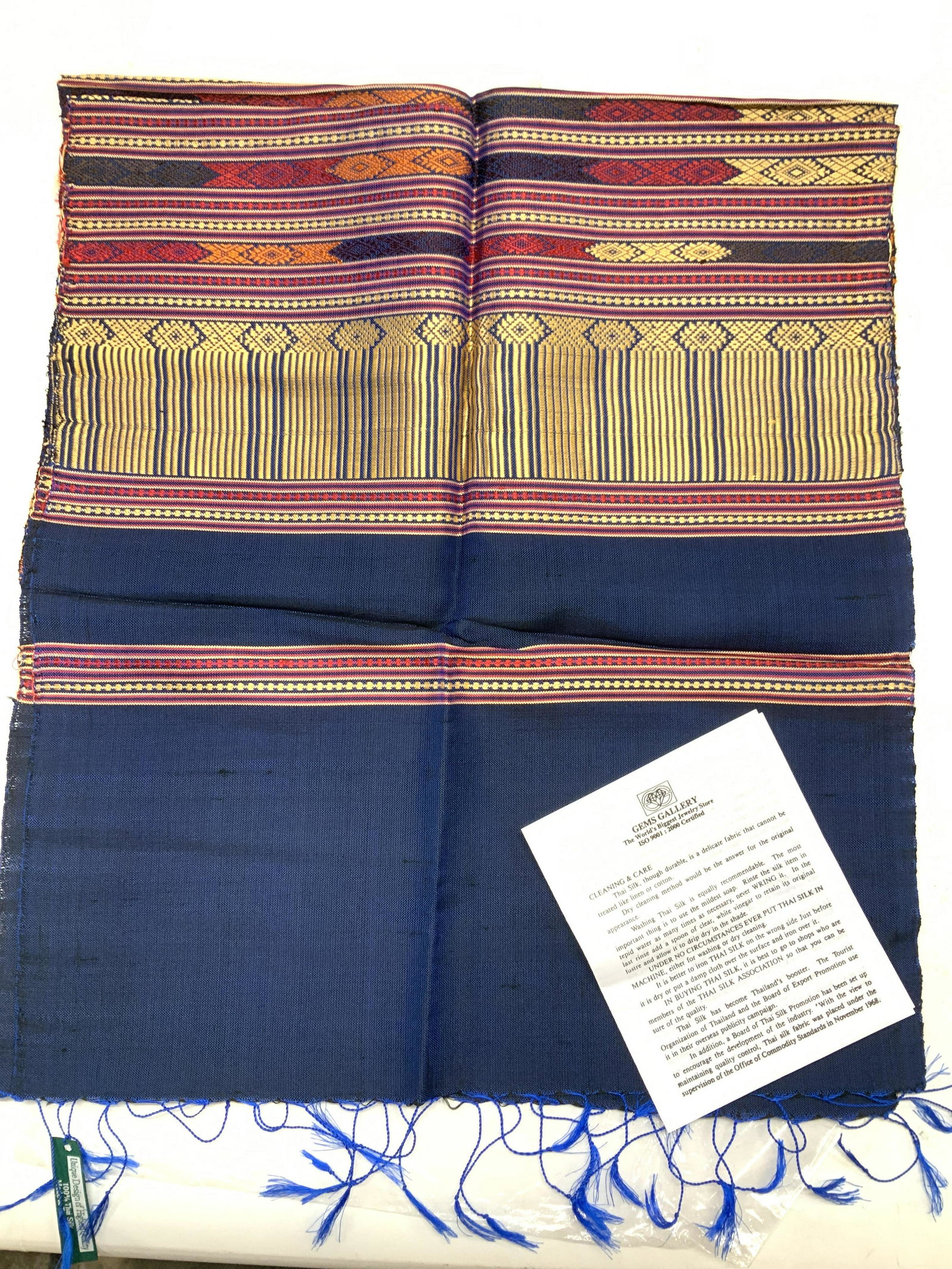 Thai Silk Wrap/ Shawl , NIP, Thailand: Gems Gallery 100% Silk Thai Wrap/ Shawl , new in package , made in Thailand. Navy blue with silk thread embroidery in colors of gold, red, brown, and orange.Royal Blue End Tassel thread. Measures 16.7