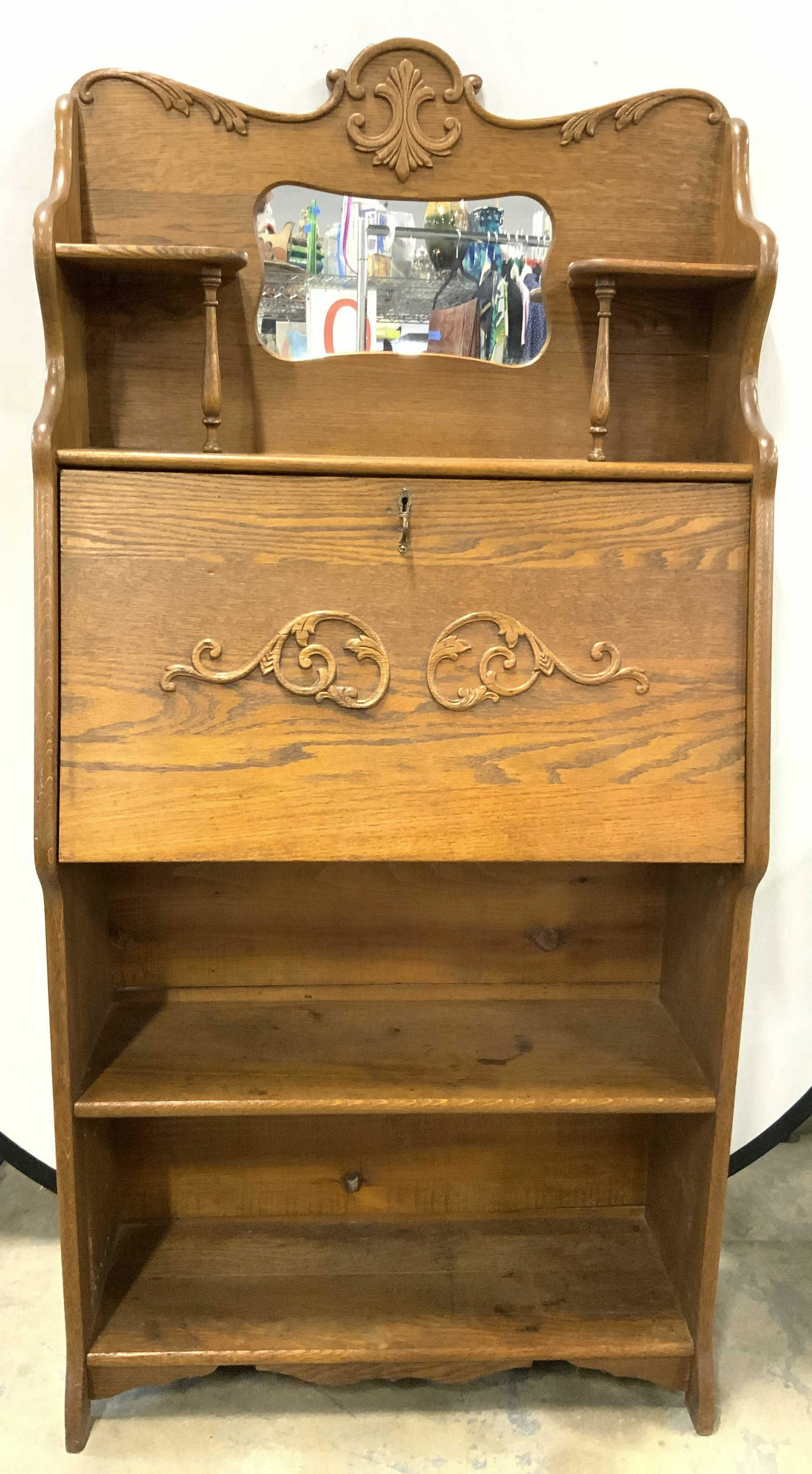 Antique Oak Larkins Flip Down Secretary Desk: Desk is antique and Oak. Piece is brown toned with carved scroll detail. Mirror at top and flip open desk area. Near top has 2 shelf areas. Lower half has shelf area. Desk includes key. Measures appro