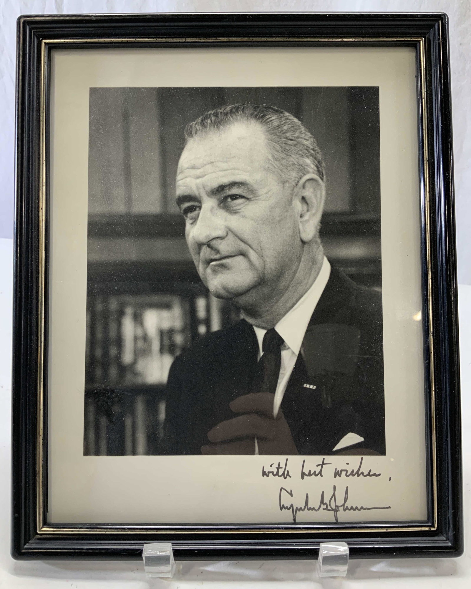 Lyndon Johnson Portrait w Secretarial Signature: Black and white portrait of President Lyndon Johnson with written secretarial remarks and signature on lower right. Reads with best wishes, Lyndon B Johnson Black plastic frame with regular glass, mea