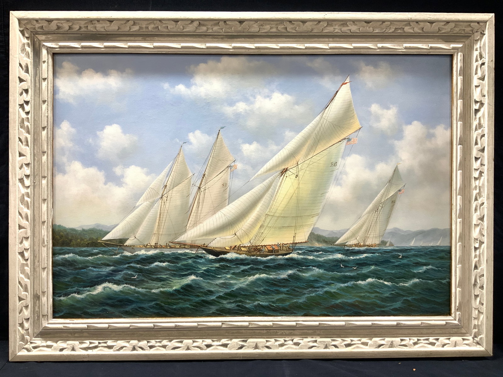 Framed Maritime Seascape Oil Painting: Framed oil painting depicting various sail boats on the sea, one marked on the sail E6 and the other F2 and a boat in the background K5 Framed in white painted carved wooden frame. Approximately 30.5 