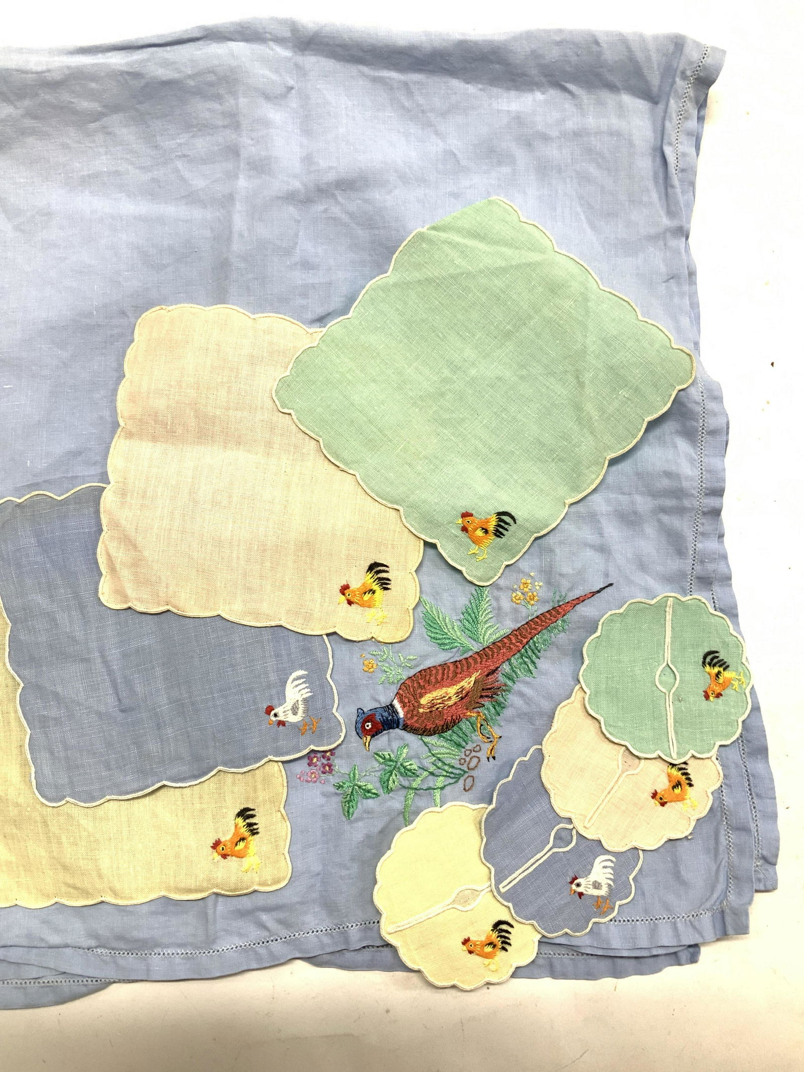 Linen Bistro Tablecloth+Linen Cocktail Napkins 9: Blue square linen tablecloth , ends are embroidered with a pheasant. Measures 32.5 x 33.5 in. 4 linen cocktail napkins with embroidered chicken in corner , one color each pastel green blue, yellow and