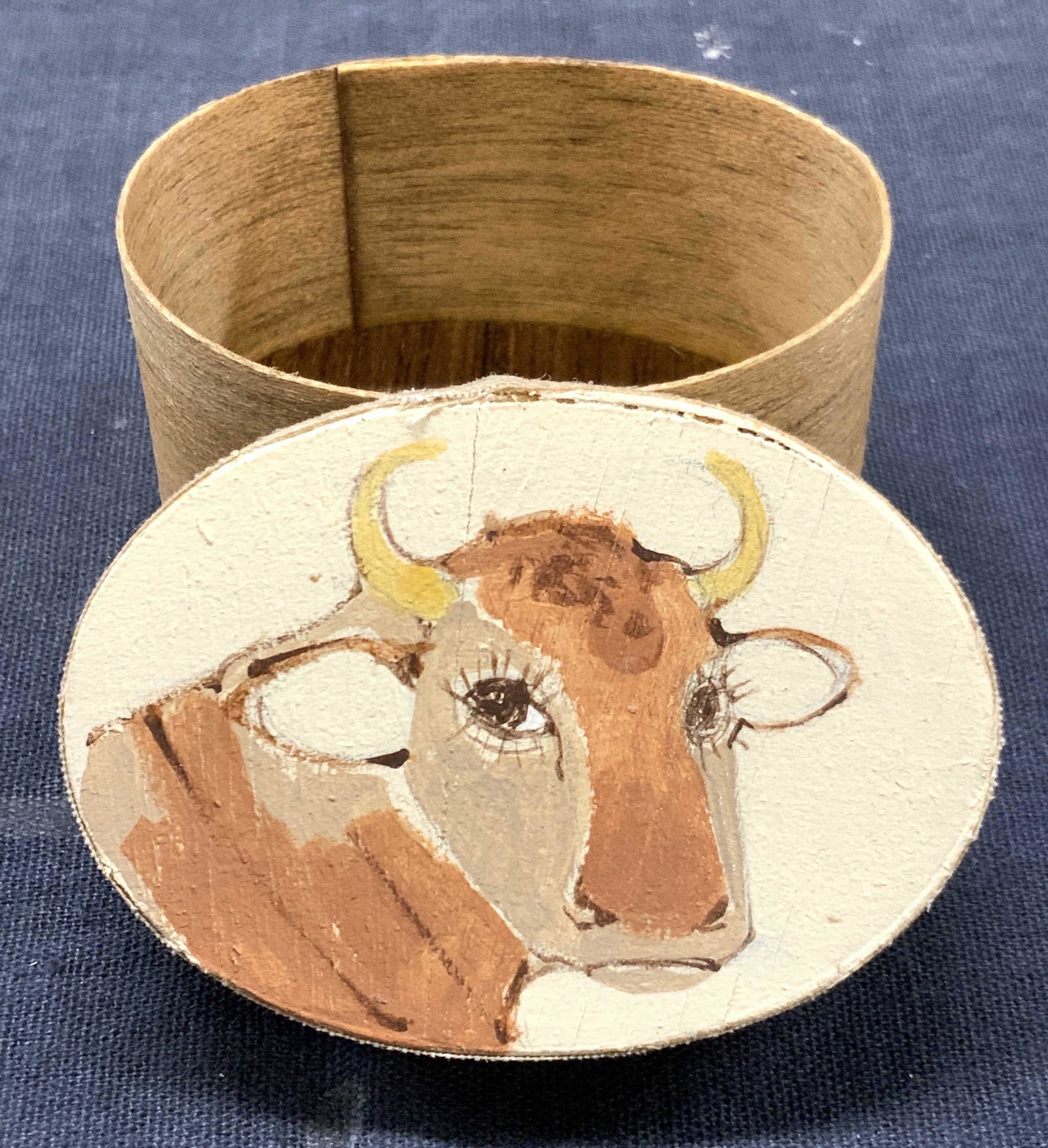 Hand Painted Wooden Cow Trinket Box: Hand painted wooden trinket box with cow head on lid. Approximately 1.25 inches tall and 2.25 inch diameter. Evident wearing to box. Hand painted box, trinket box, pill box, hand painted wooden box, w