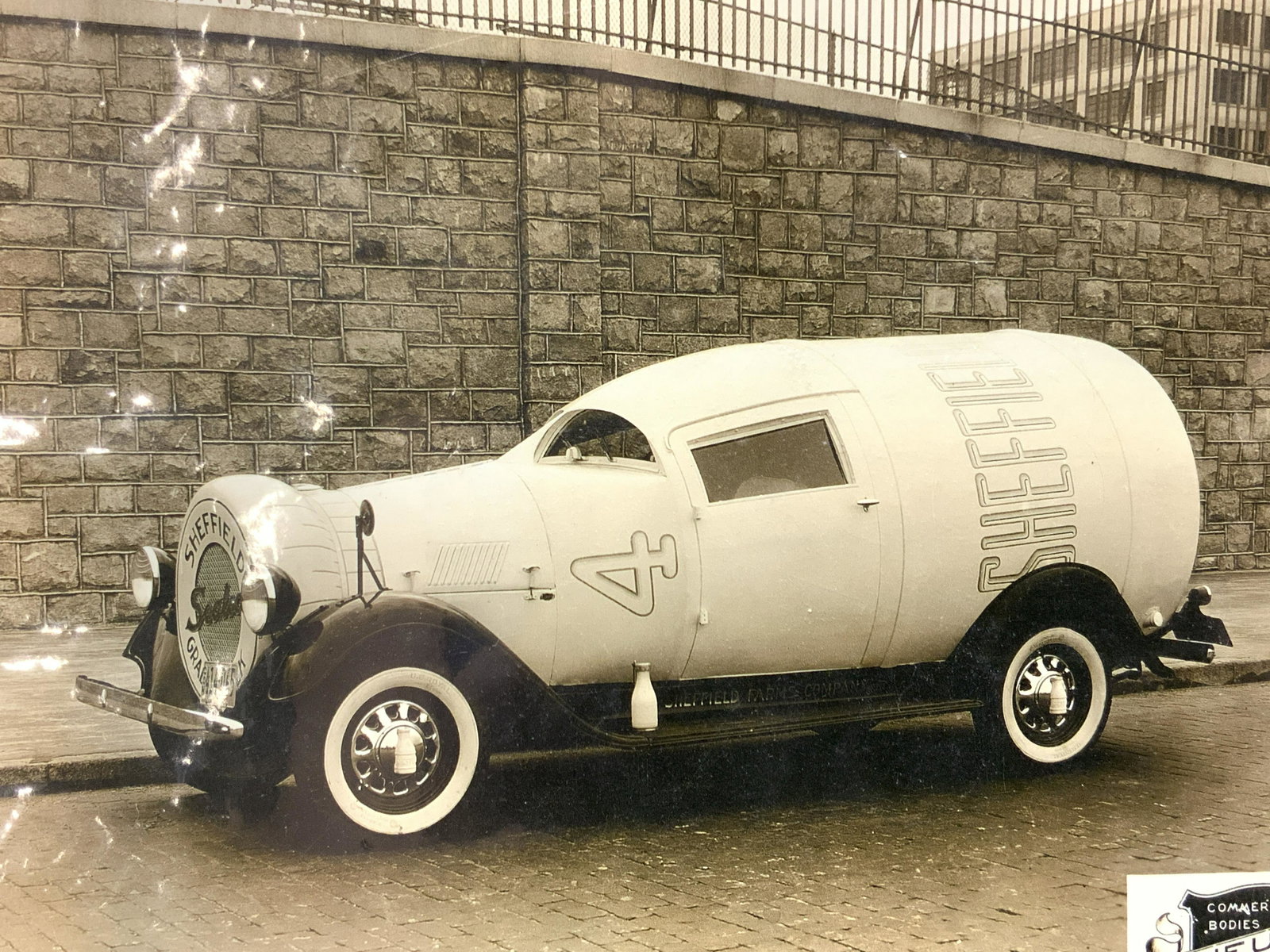 Vintage Sheffield Milk Bottle Mobile Photograph: Marked on lower right corner Commercial bodies Theurer, New York, NY, North Bergen NJ. Backside of photo is stamped MtC displays and graphics. Depicts an automobile in the shape of a milk bottle with 