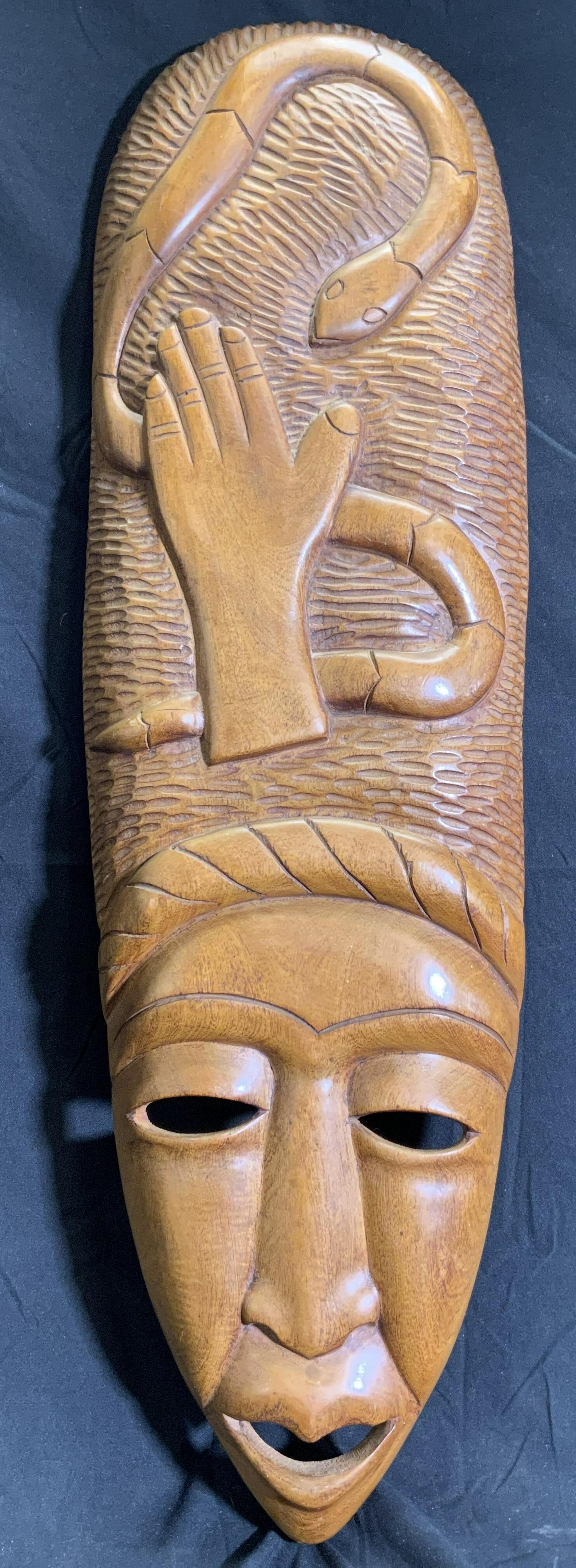 Vintage Carved Wooden Tribal Mask: Tribal mask is vintage and wooden. Piece is beige toned, depicts head with head dress with snake & hand figure 32 inches tall 9.5 inches wide. Mask, face mask, tribal mask, wooden mask, vintage mask, 